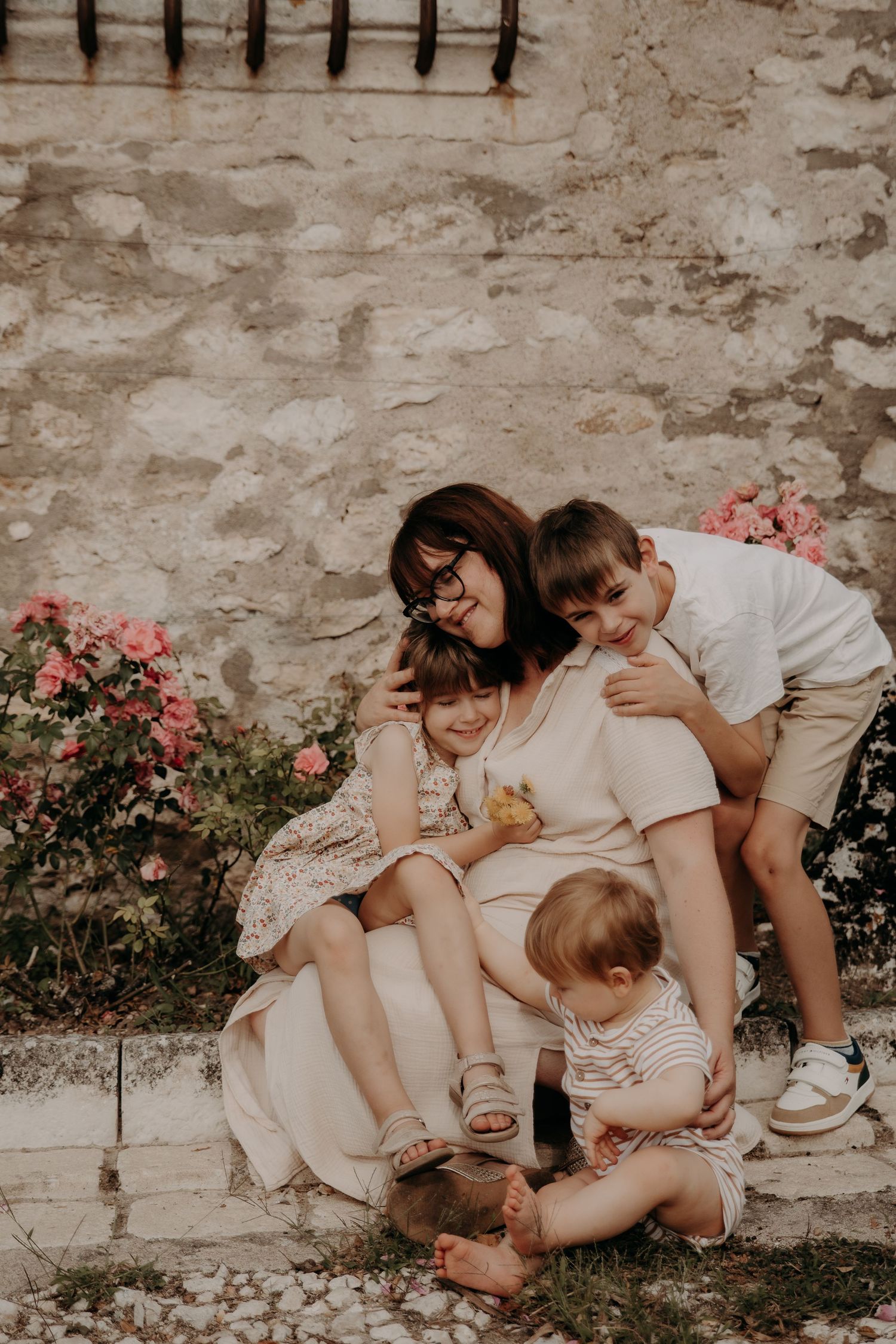 Family sharing candid moment on stone steps with blooming pink flowers.