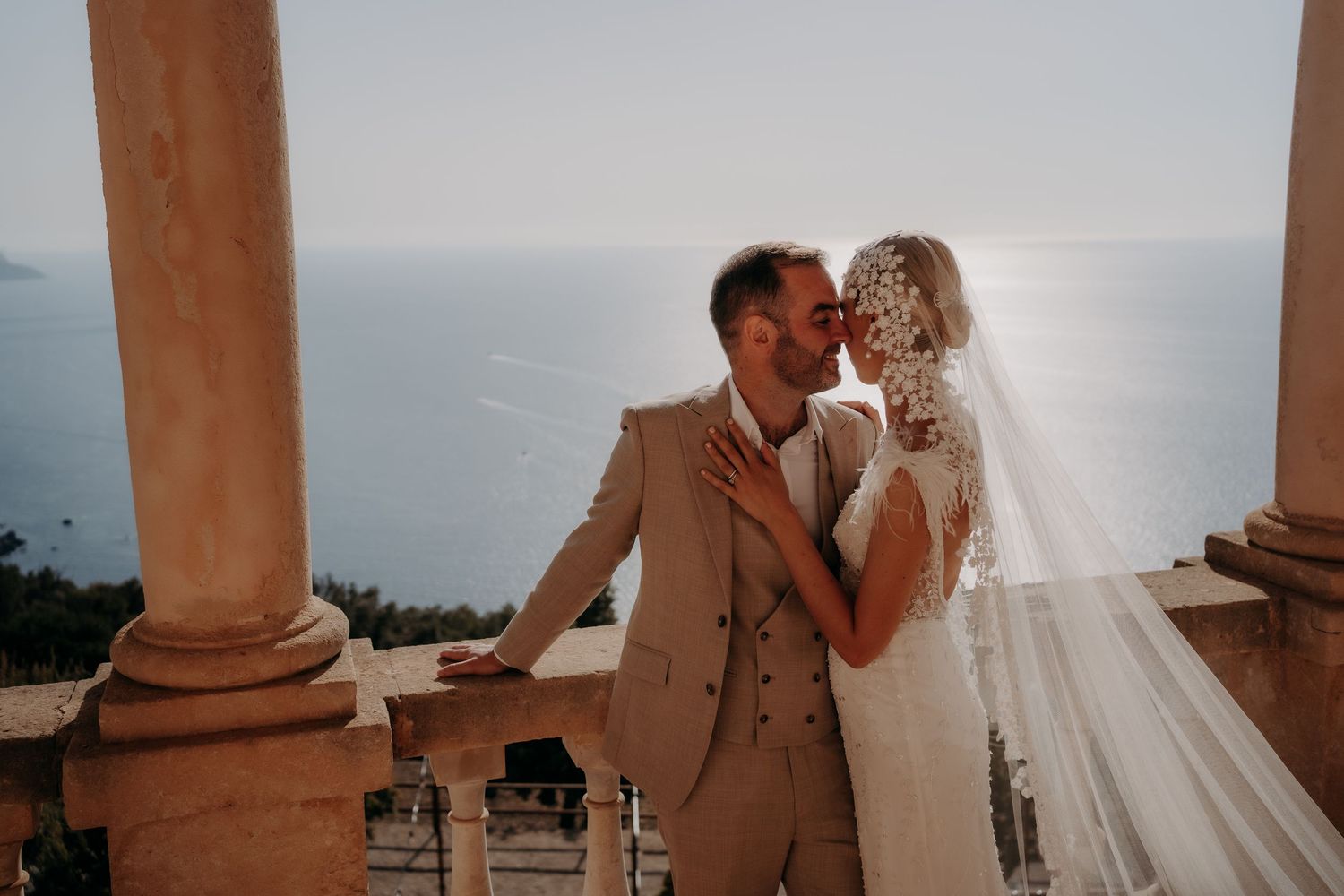 Romantic moment captured under Mediterranean-style archways with flowing veil.