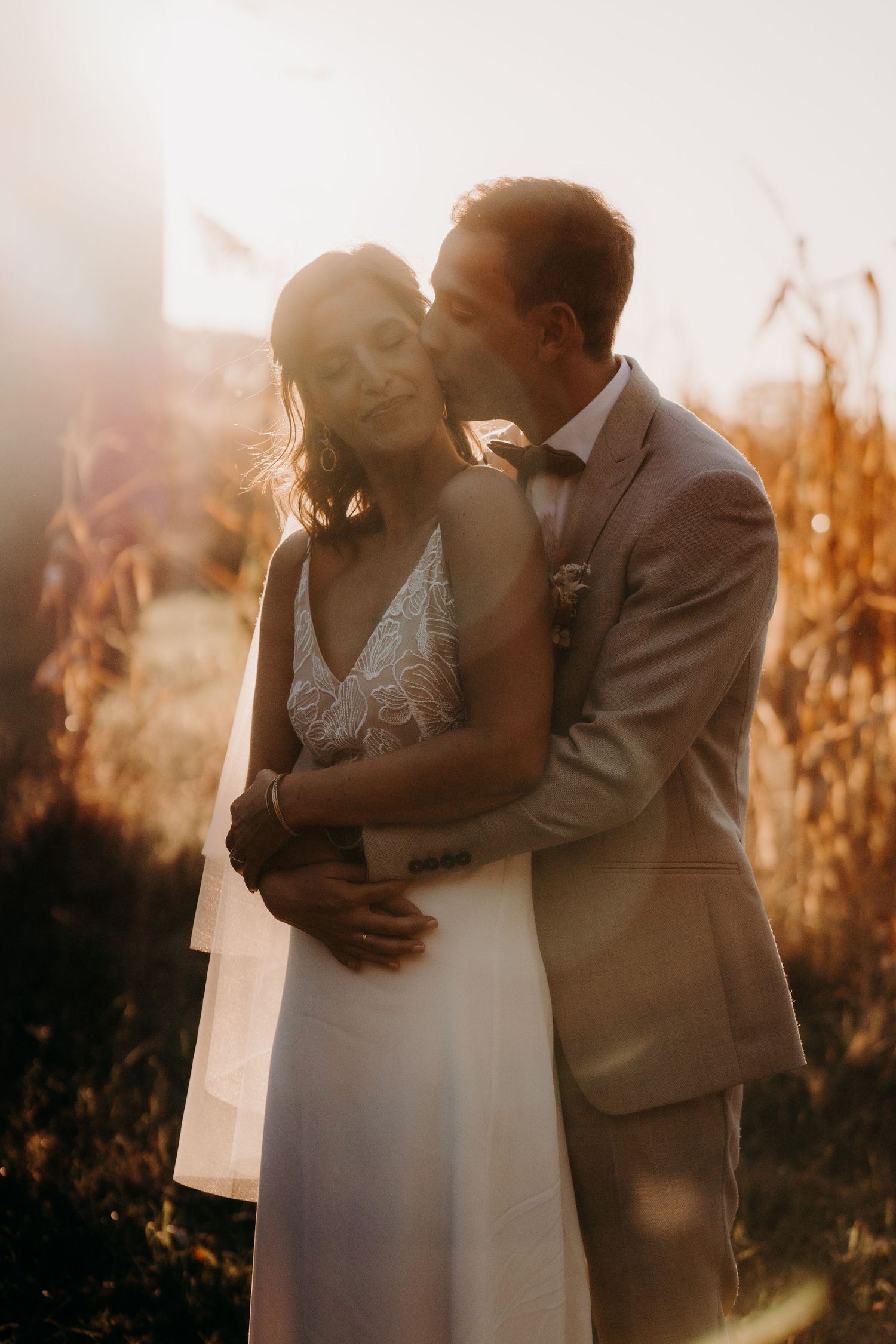 Intimate wedding portrait during golden hour in a cornfield.