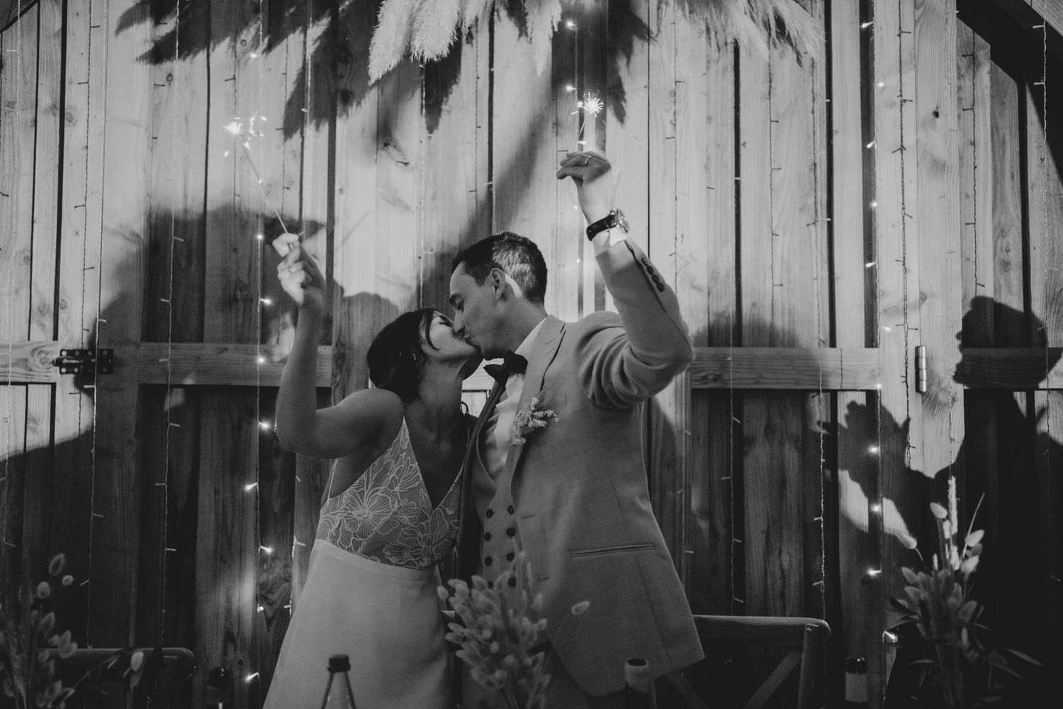 Black and white wedding photo with dramatic shadows cast on wooden wall.