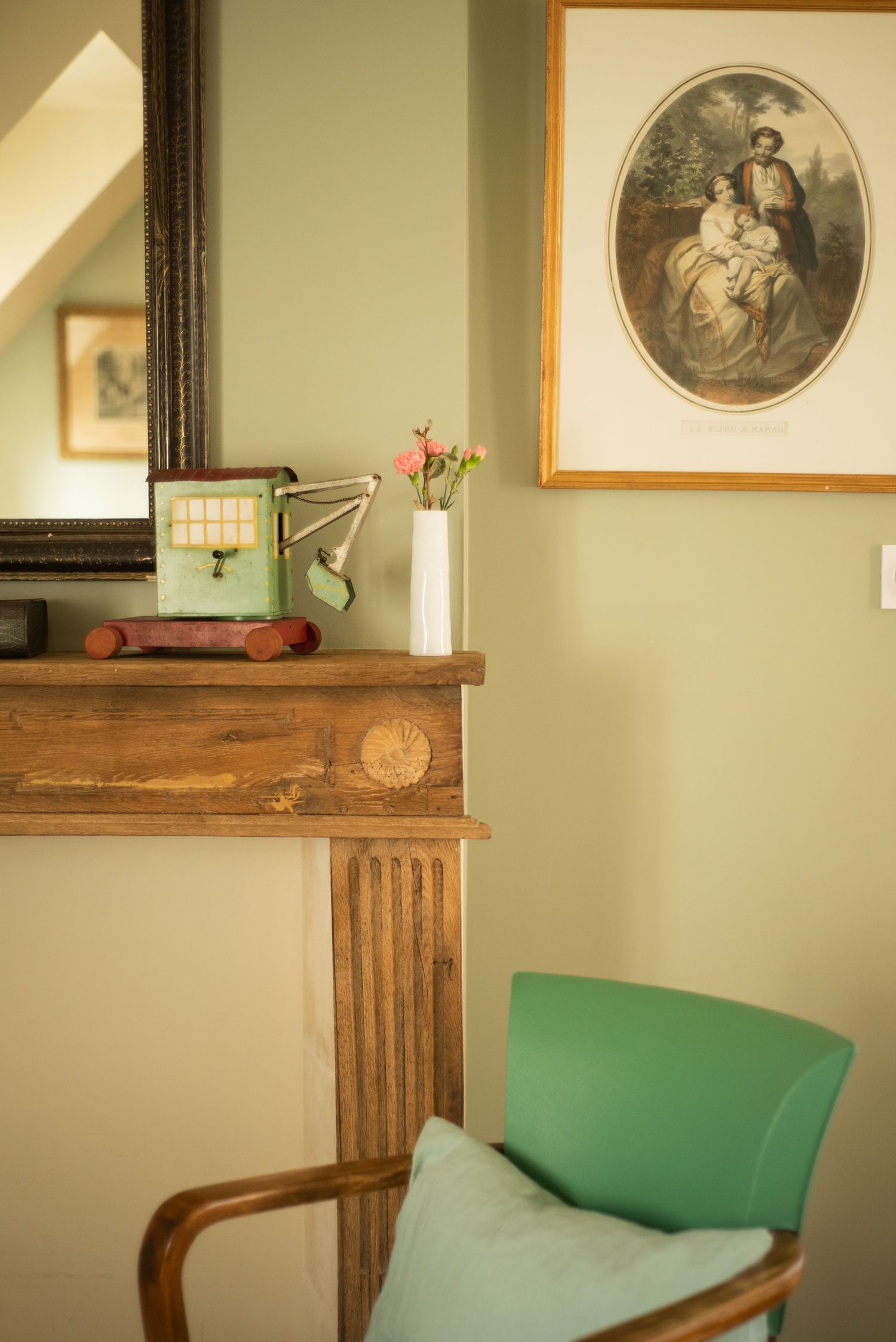 Vintage-style room with mint green chair and framed artwork on pale walls.
