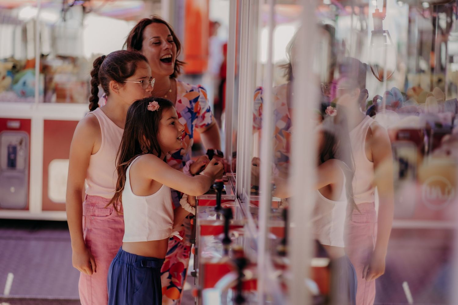 Family having fun at arcade while playing claw machine games together.