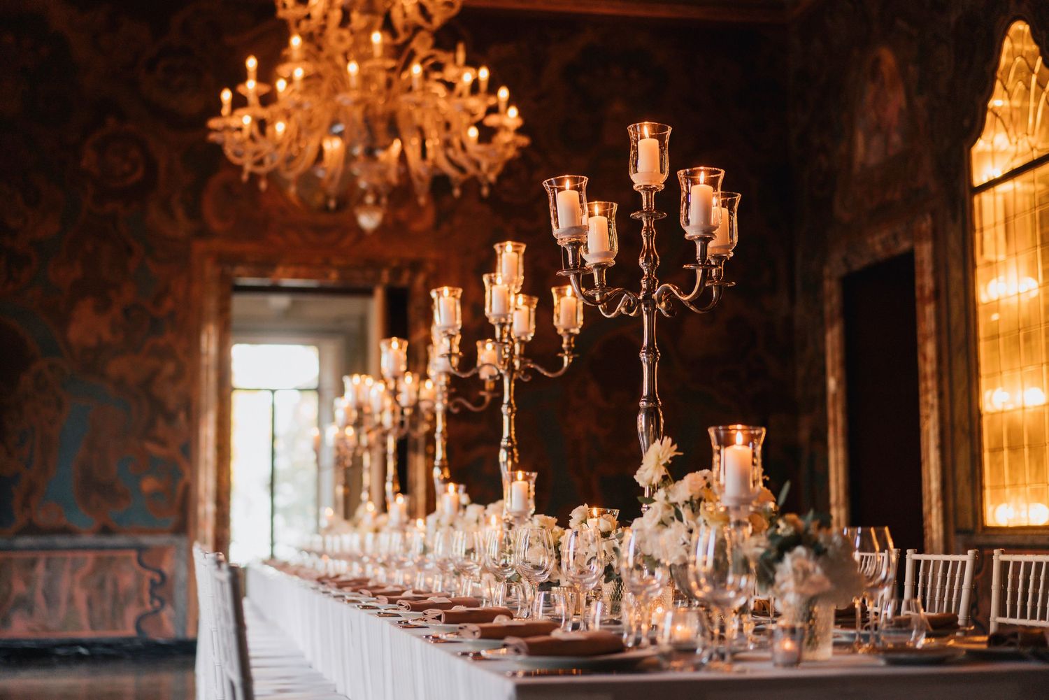 Elegant reception hall decorated with crystal chandeliers and warm lighting.