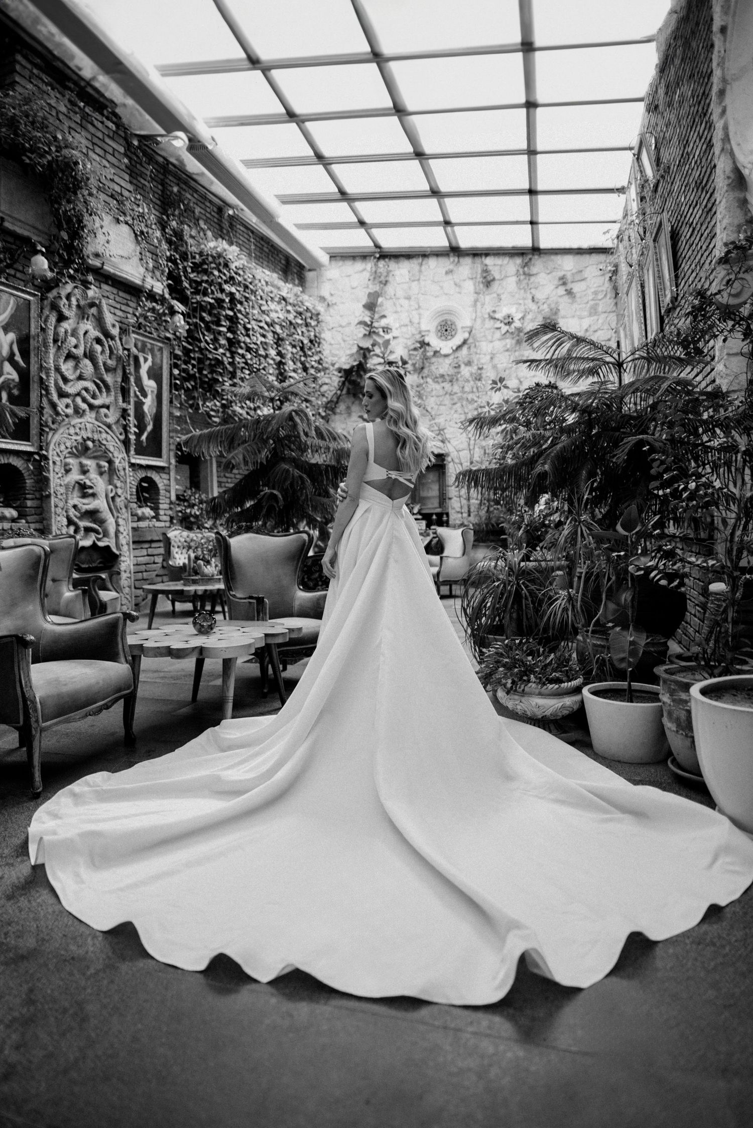 Black and white photos of a wedding dress displayed in a greenhouse setting with dramatic lighting.
