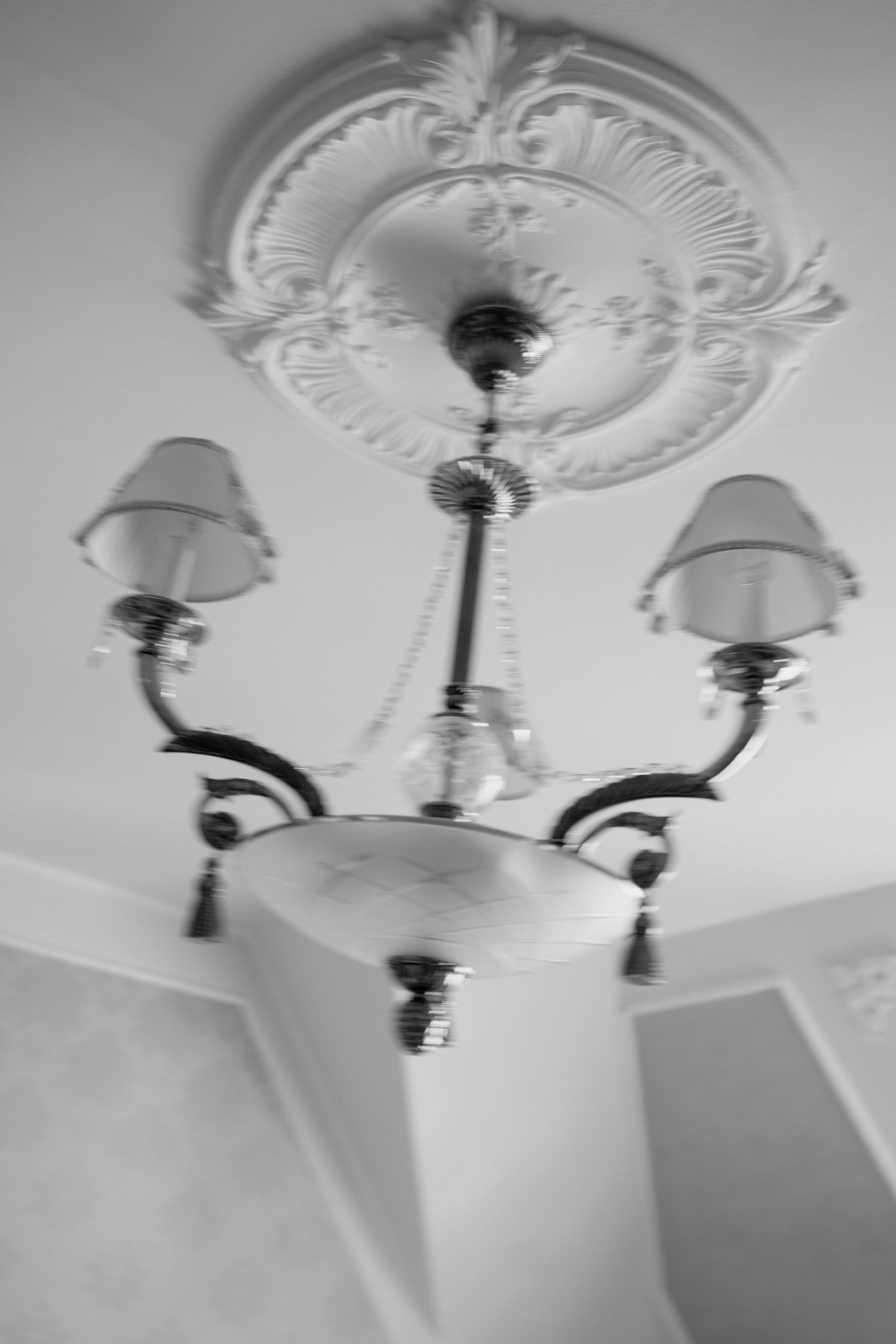 Series of ornate white ceiling medallions with vintage light fixtures in a classic interior.