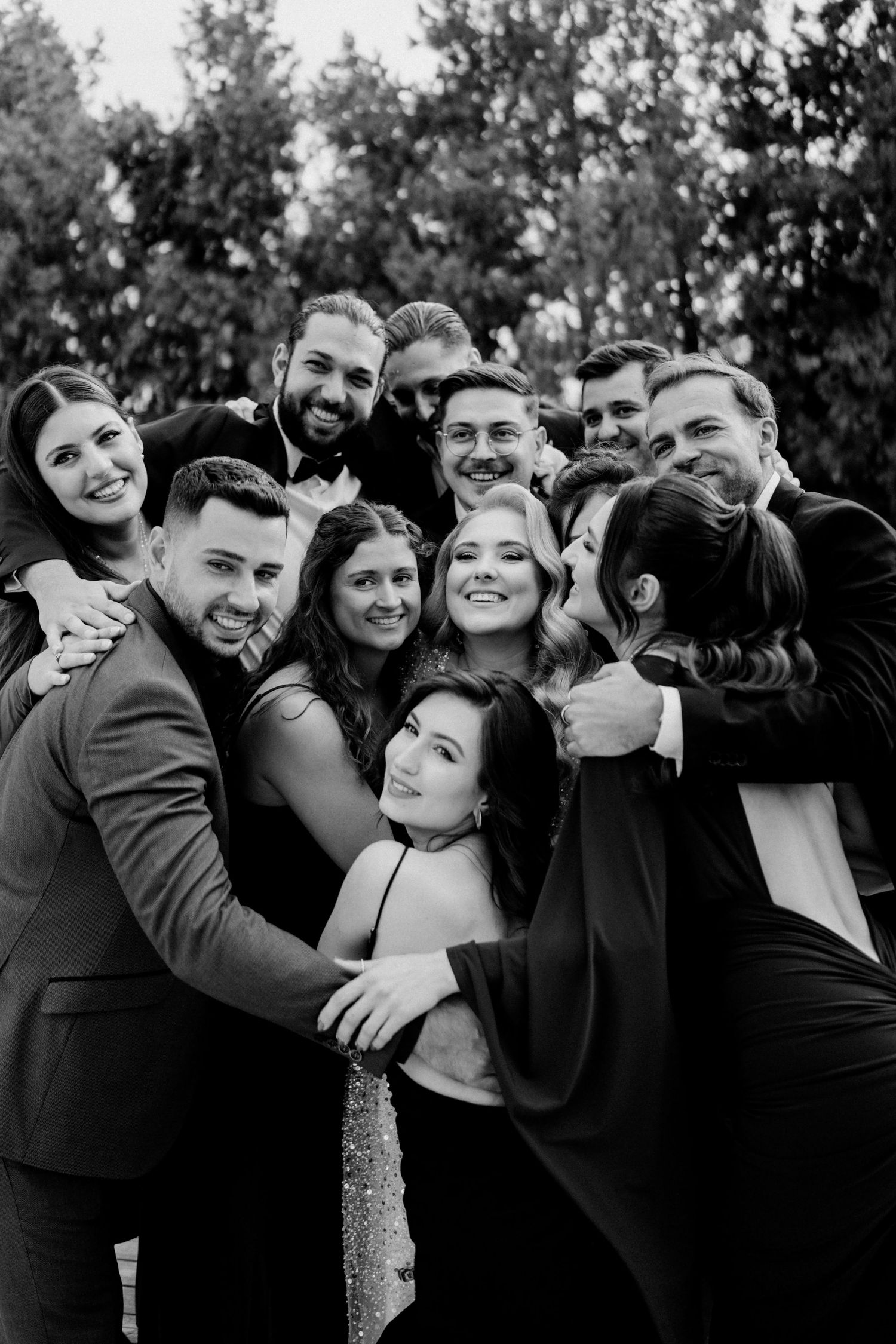 Wedding party poses for fun group photos outdoors in black and white.