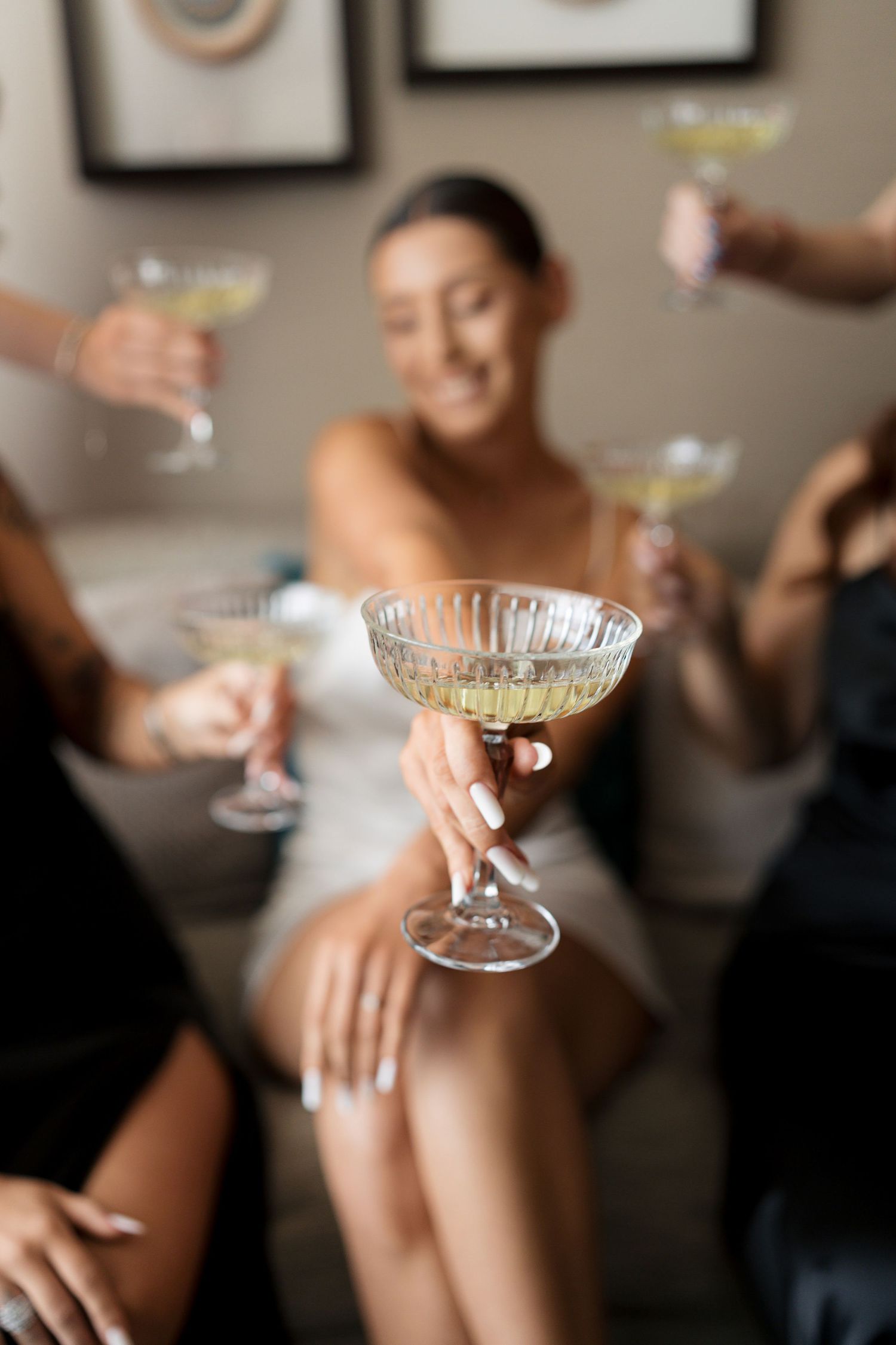 Elegant champagne glasses raised in celebration during wedding preparations.