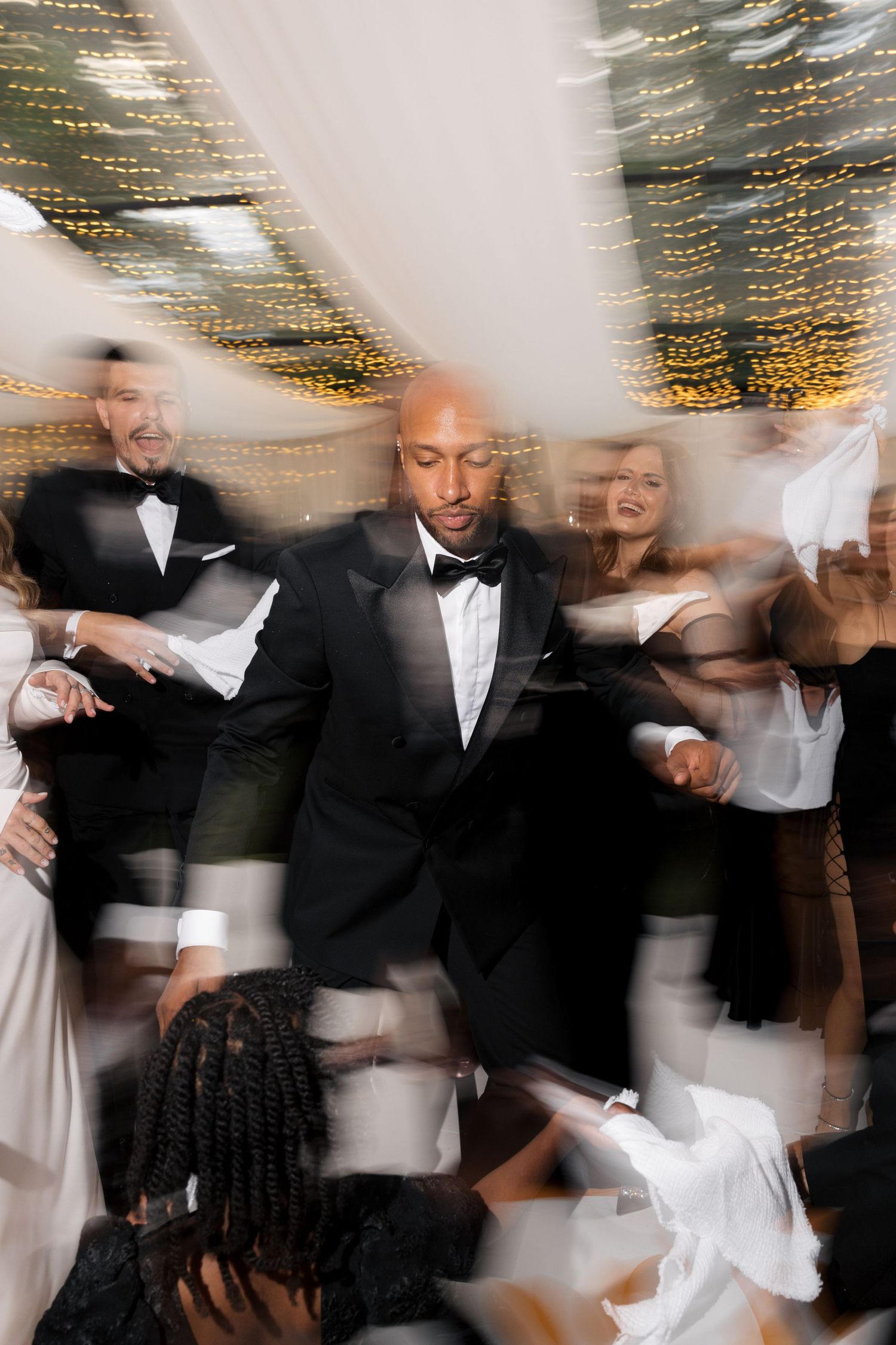 Motion blur wedding dance photos showing celebration under twinkling lights.