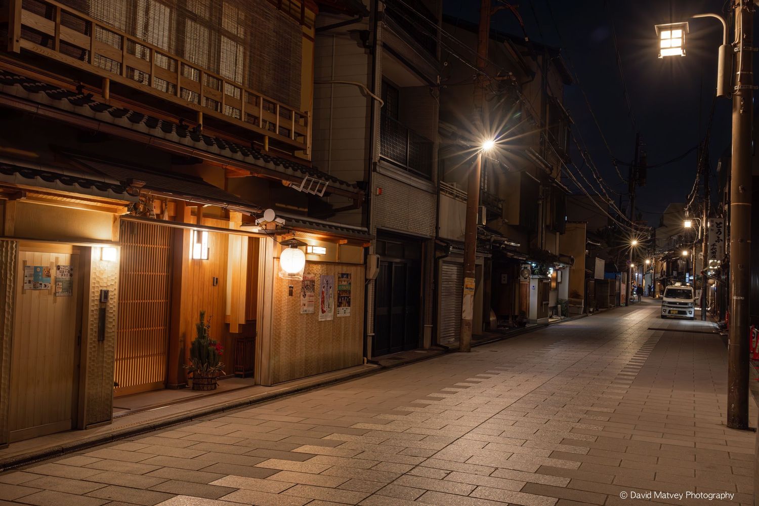 Quiet traditional Japanese street at night illuminated by warm lantern lights in Kyoto.