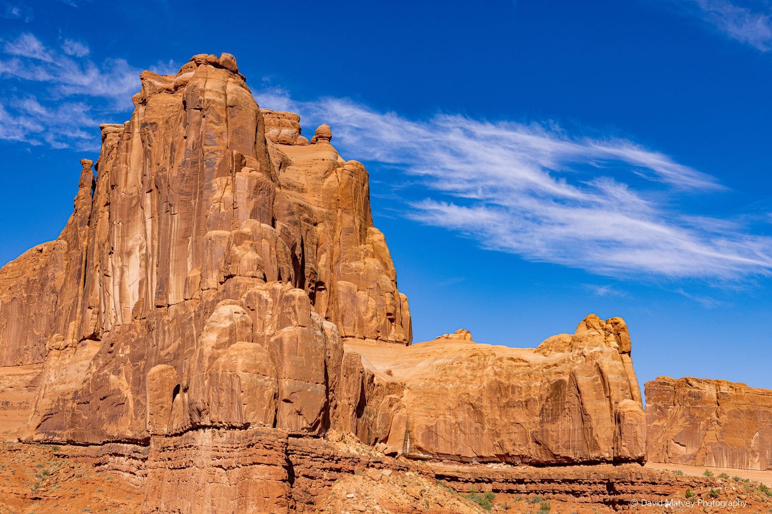 Towering red sandstone rock formation against a vivid blue sky in Arches National Park, Utah.