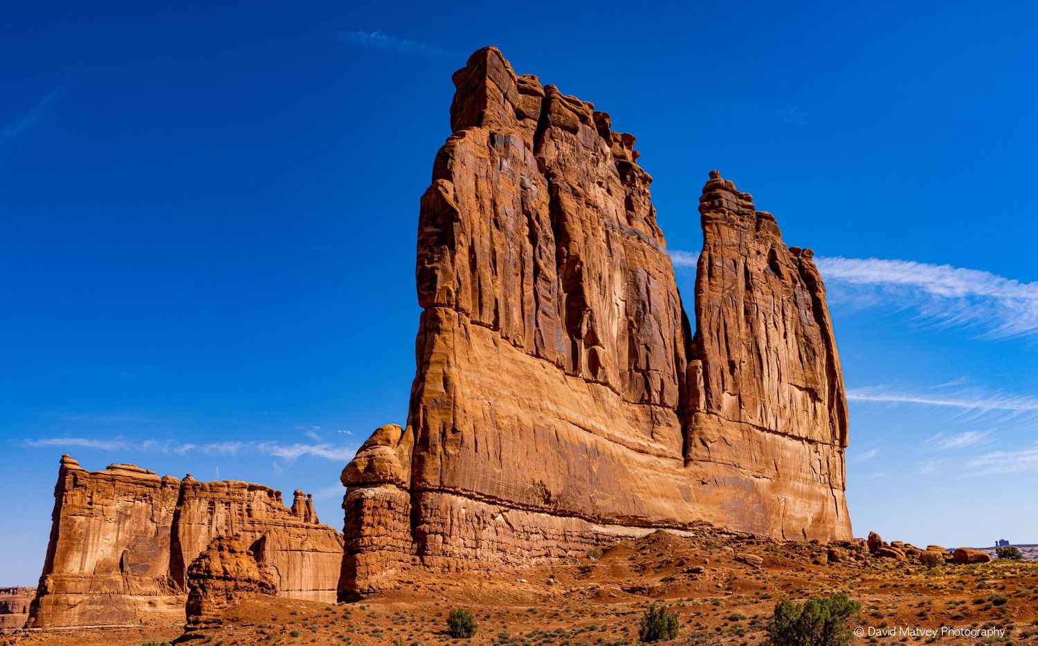 Towering red sandstone rock formation against vivid blue sky in Arches National Park, Utah.