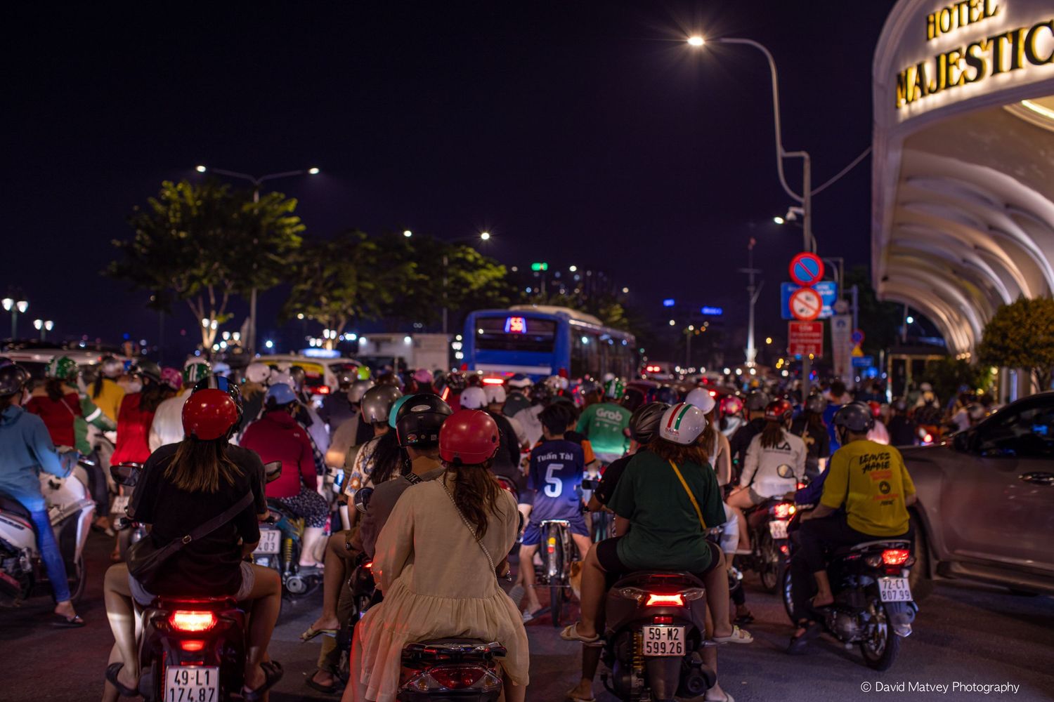 Busy night traffic of motorcycles and scooters on a crowded urban street in Vietnam near Hotel Majestic.