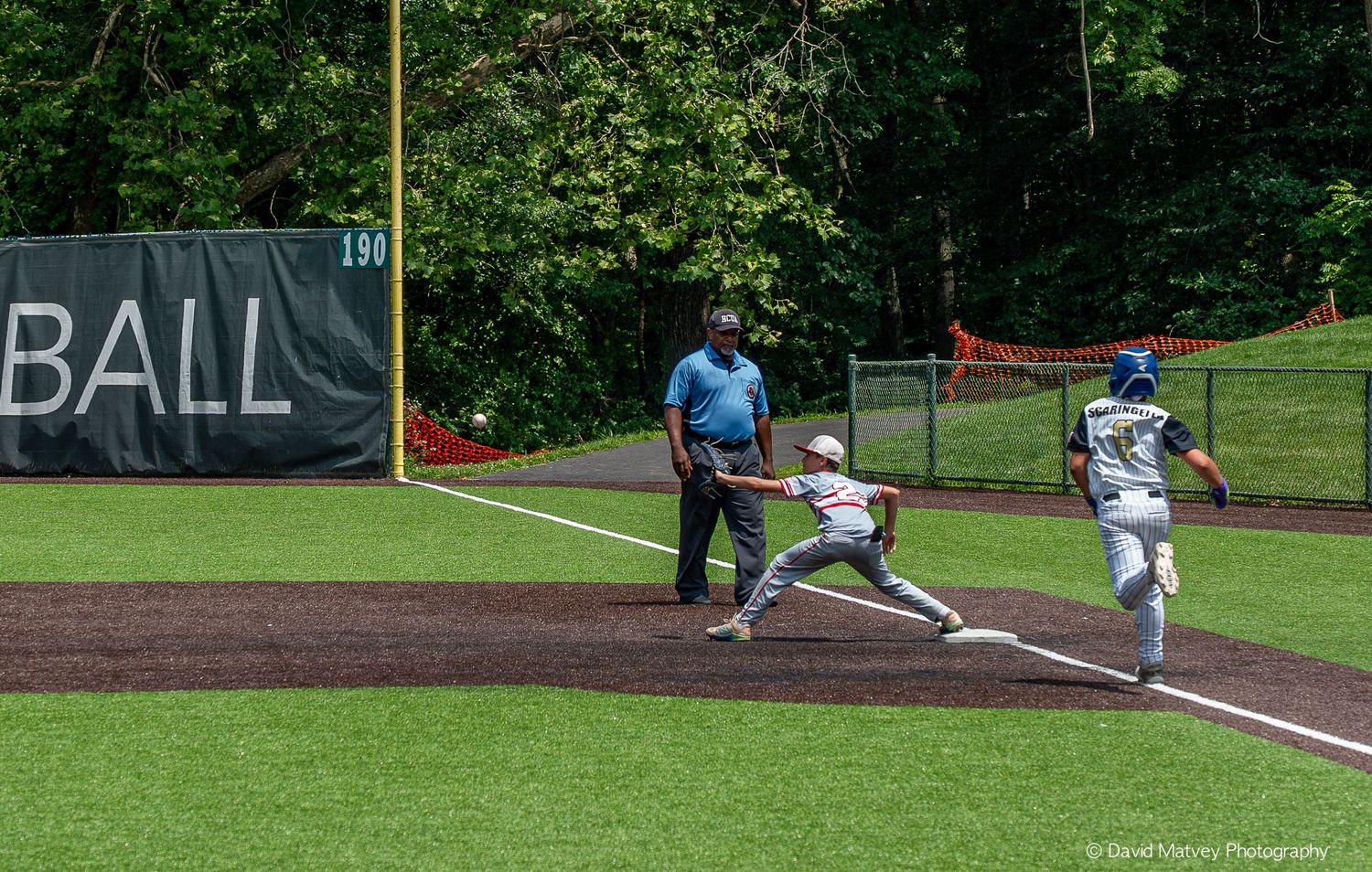 Baseball player stretching at first base to make a play during a sunny outdoor game.