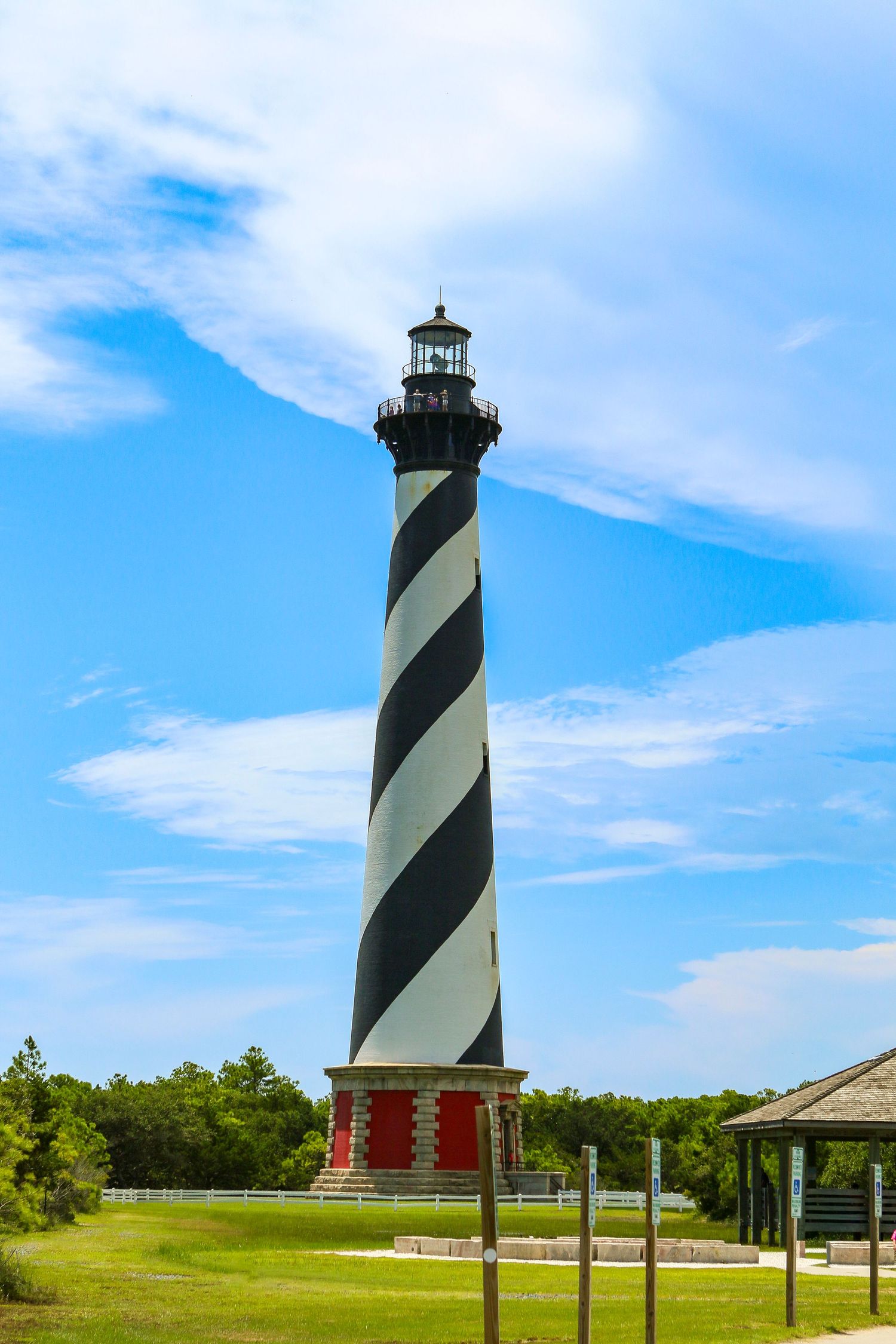 Iconic black and white spiral striped Cape Hatteras Lighthouse under blue cloudy sky.