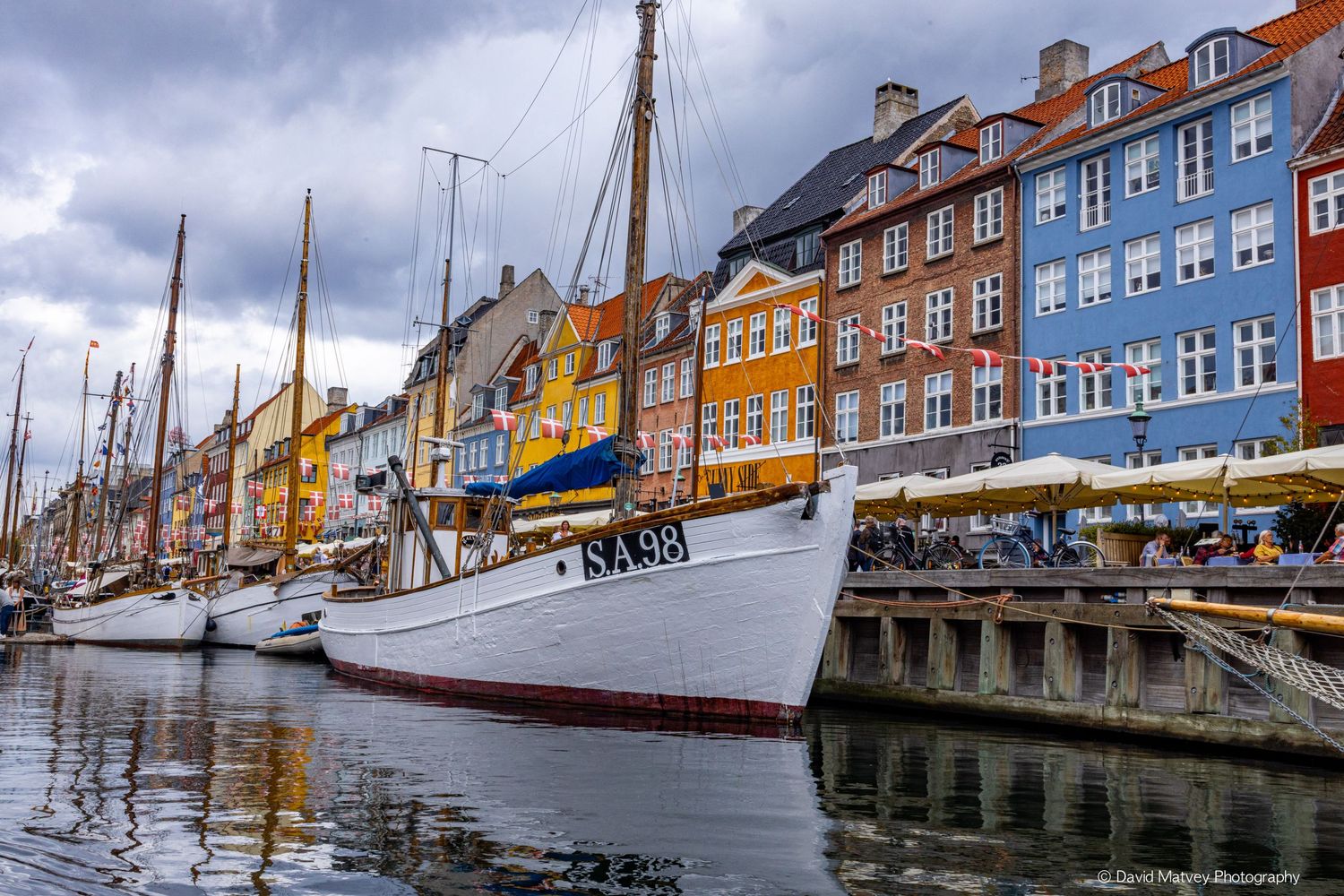 Colorful historic buildings and sailing boats reflected in the calm waters of Nyhavn canal, Copenhagen.