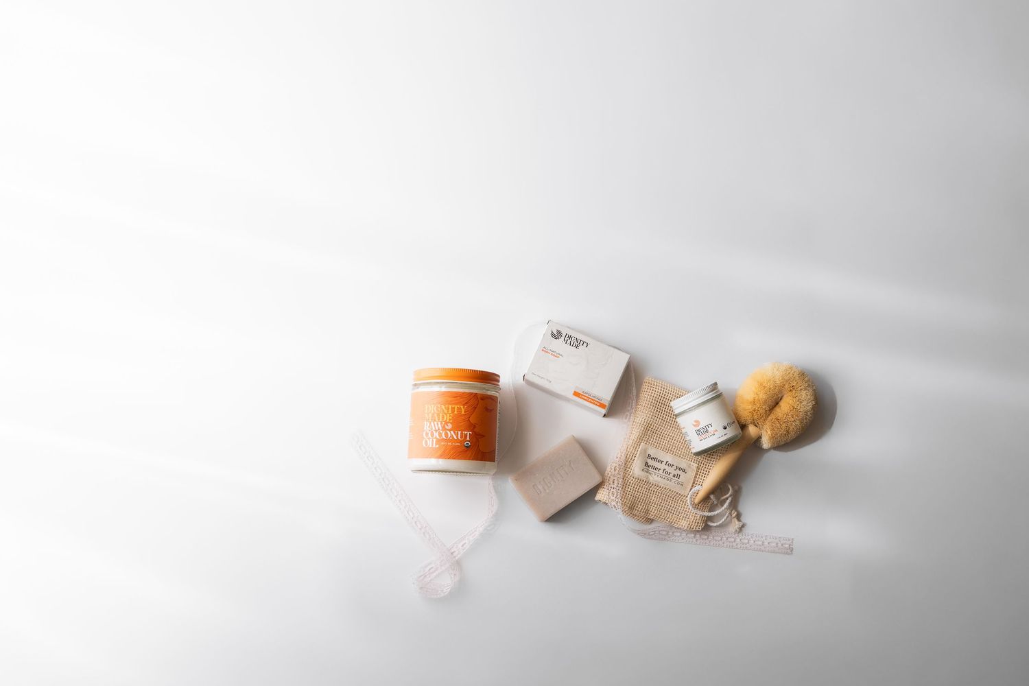 Flatlay of natural skincare products including orange jar, soap bars, and sponge on white.