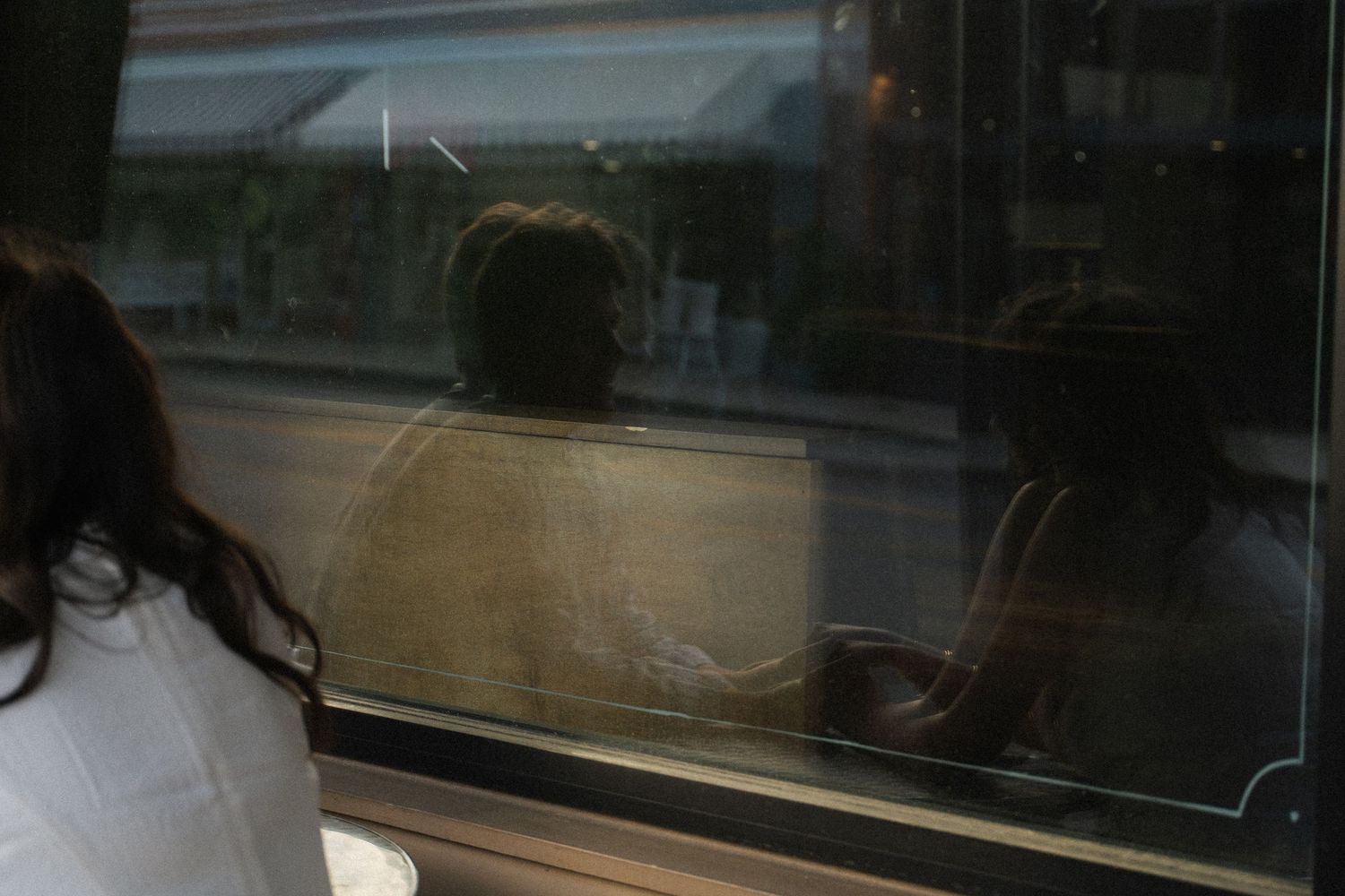 Reflective window shot of a couple sitting at a table.