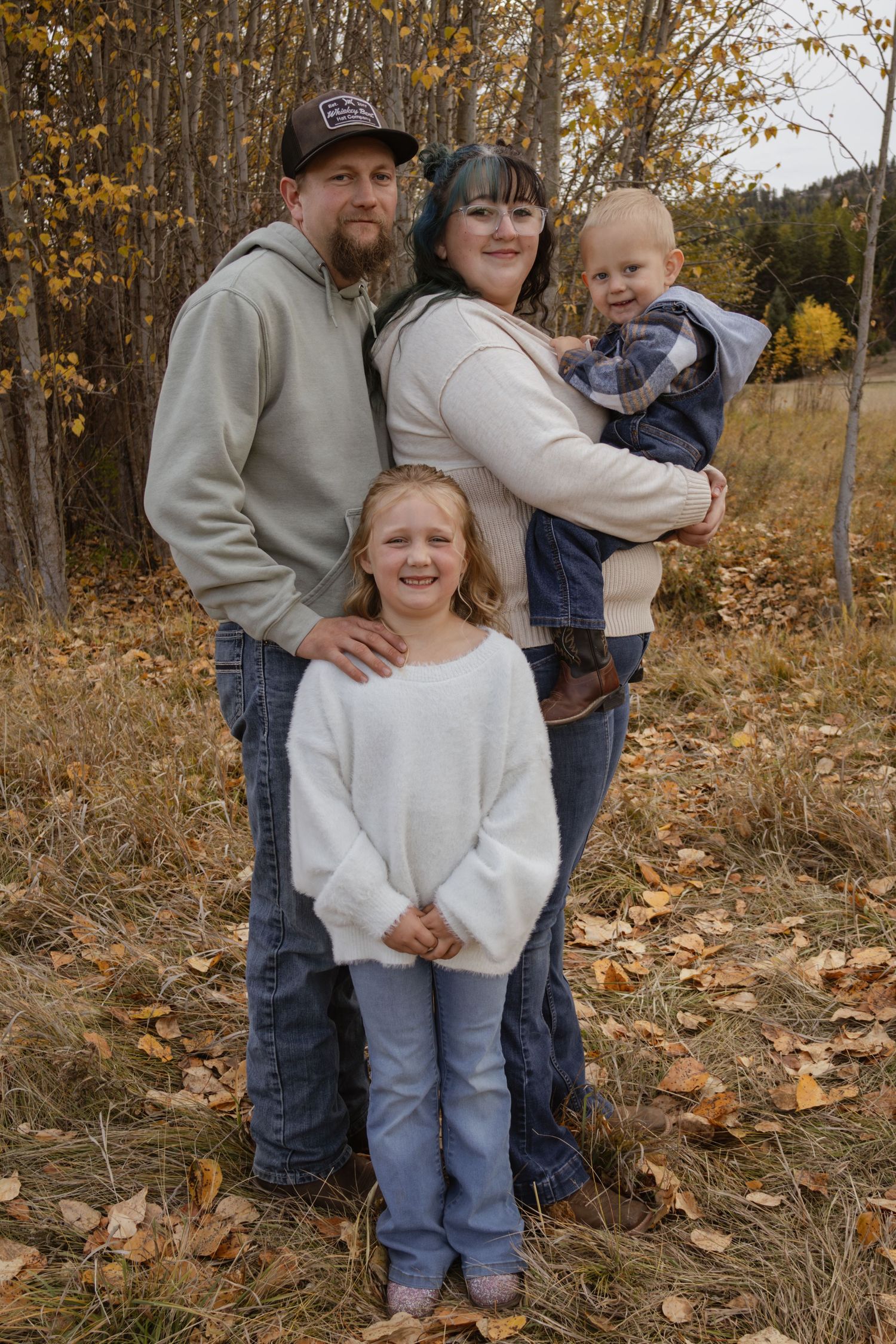 A family of four standing together smiling for the camera during a family session in Kalispell Montana
