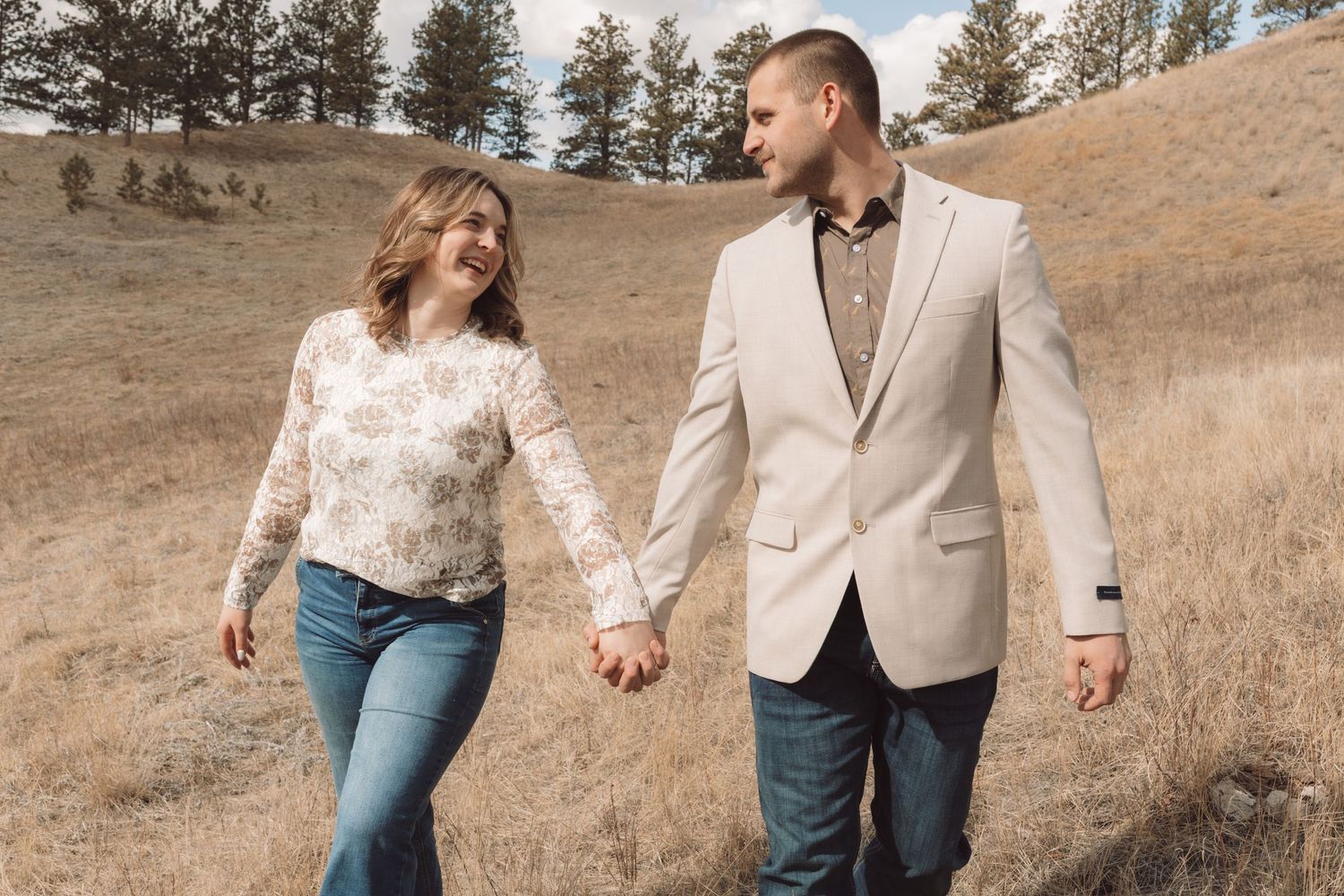 A couple walking looking at each other on a hillside during an engagement session in Havre, Mt