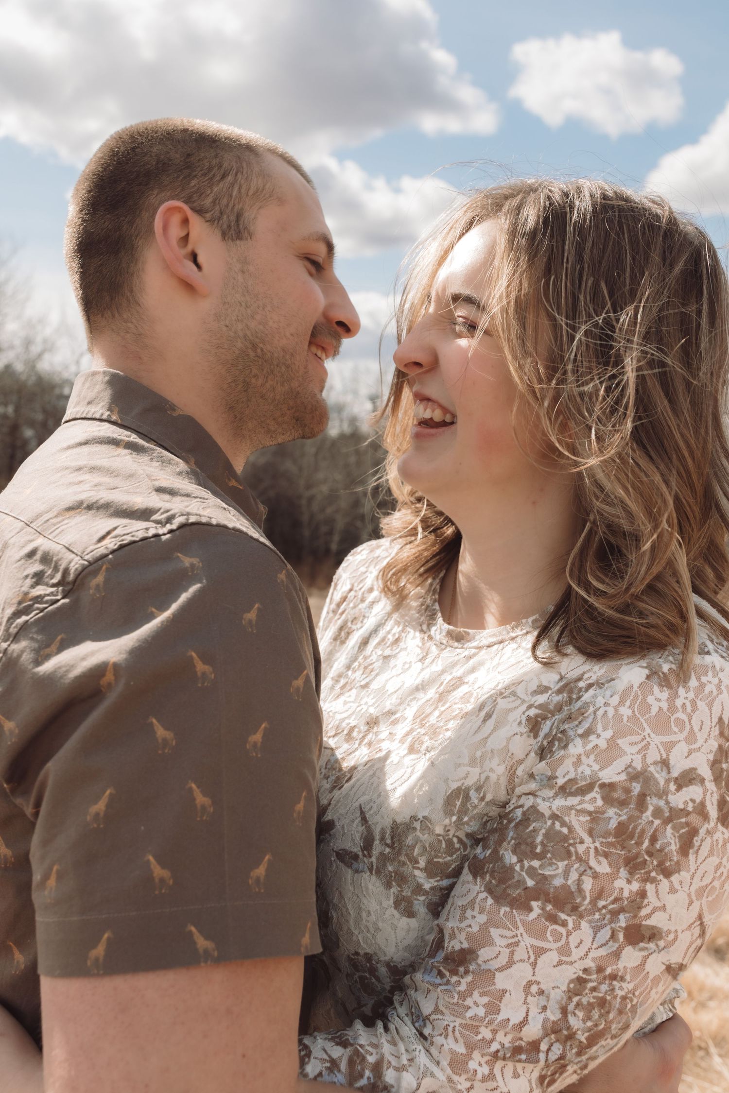 A couple laughing together in the sunshine during an engagement session in Havre, Mt