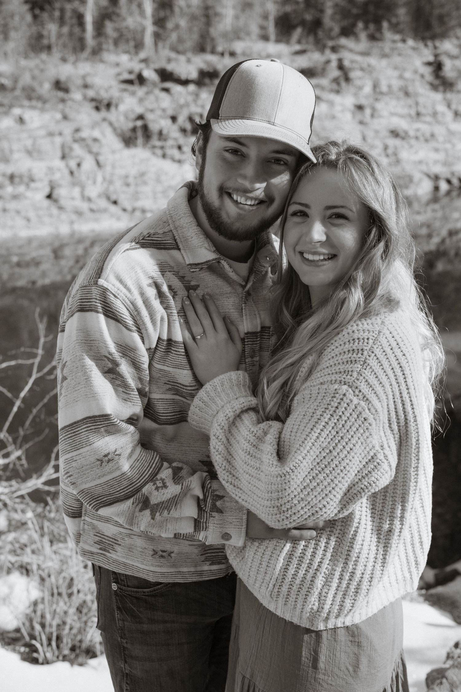 An engaged couple hugging and smiling at the camera during a couples session in West Glacier Montana