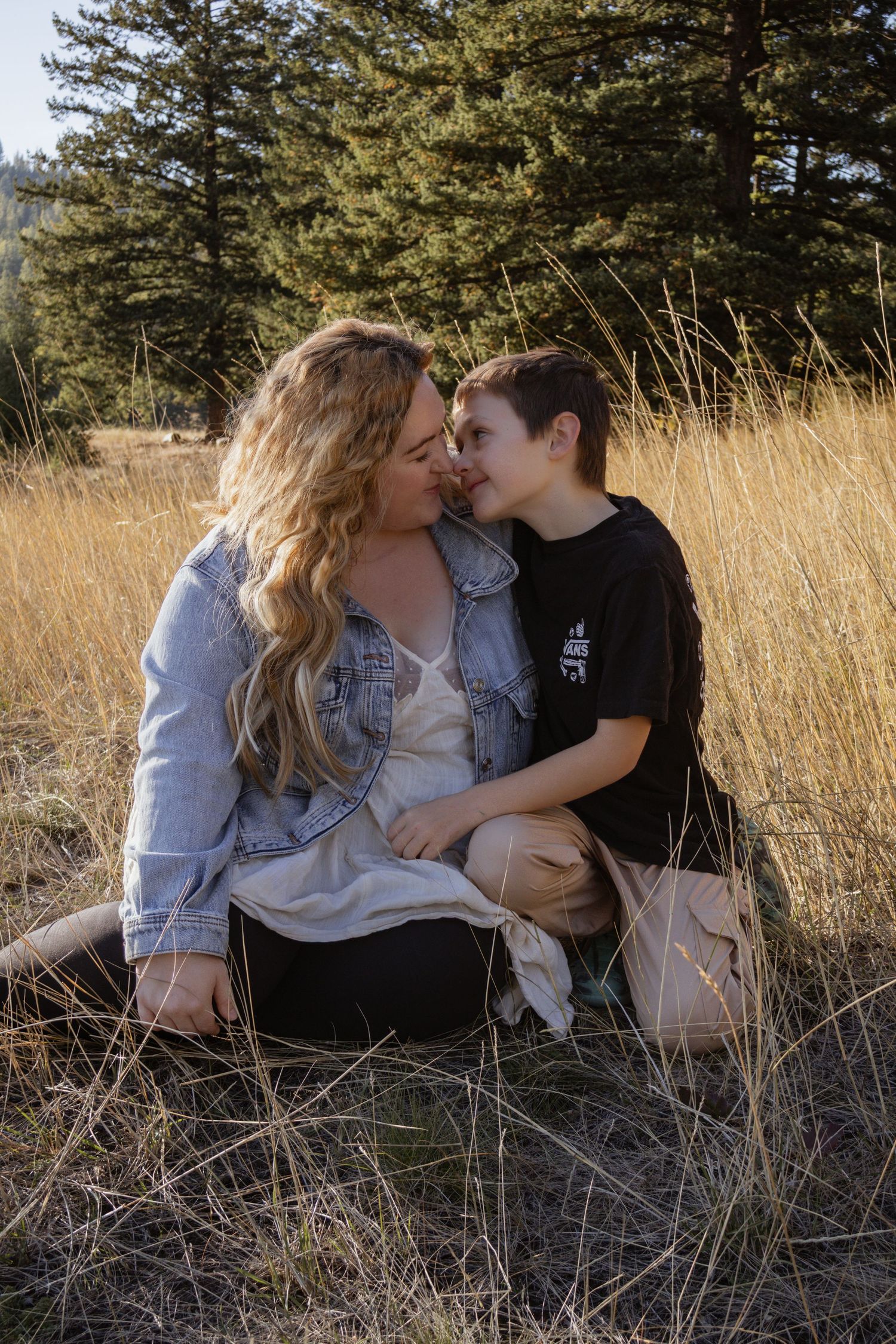 A mother sitting with her son nose to nose in a field during a mommy and me session in Kalispell Montana