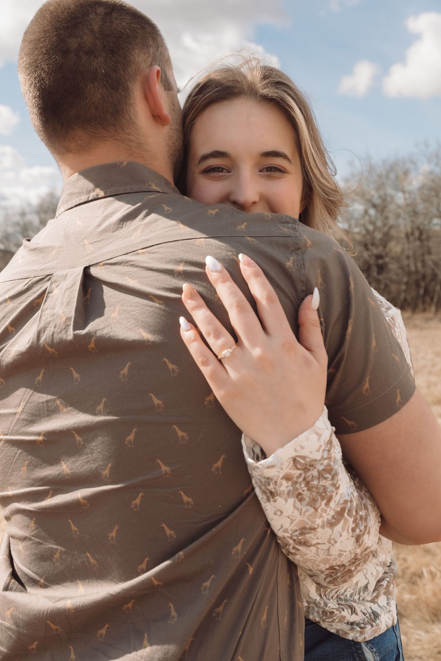 A couple hugging while the woman shows off her ring during an engagement session in Havre, Mt