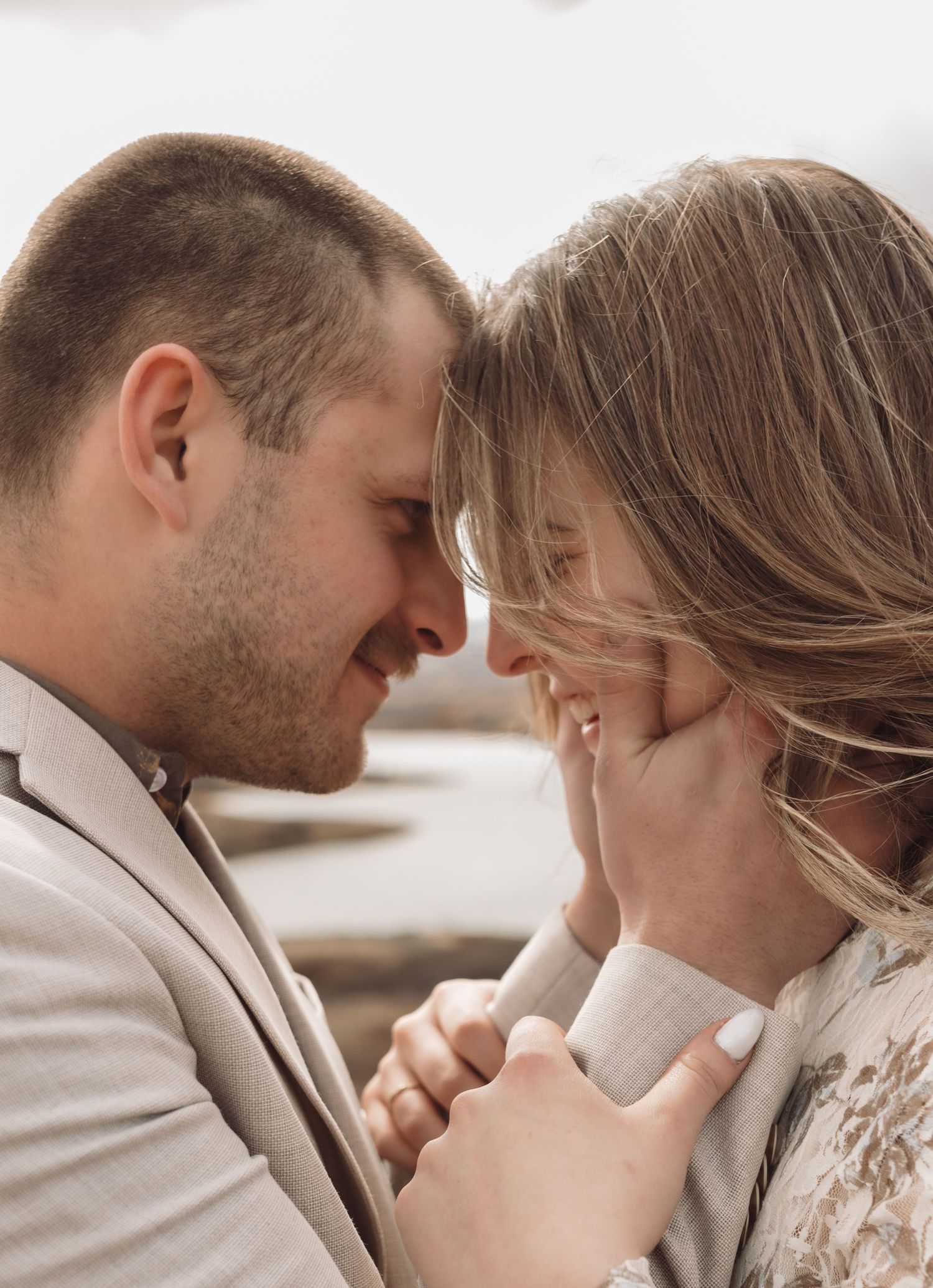 A man embracing his fiancés face while she smiles at him during an engagement session in Havre, Mt