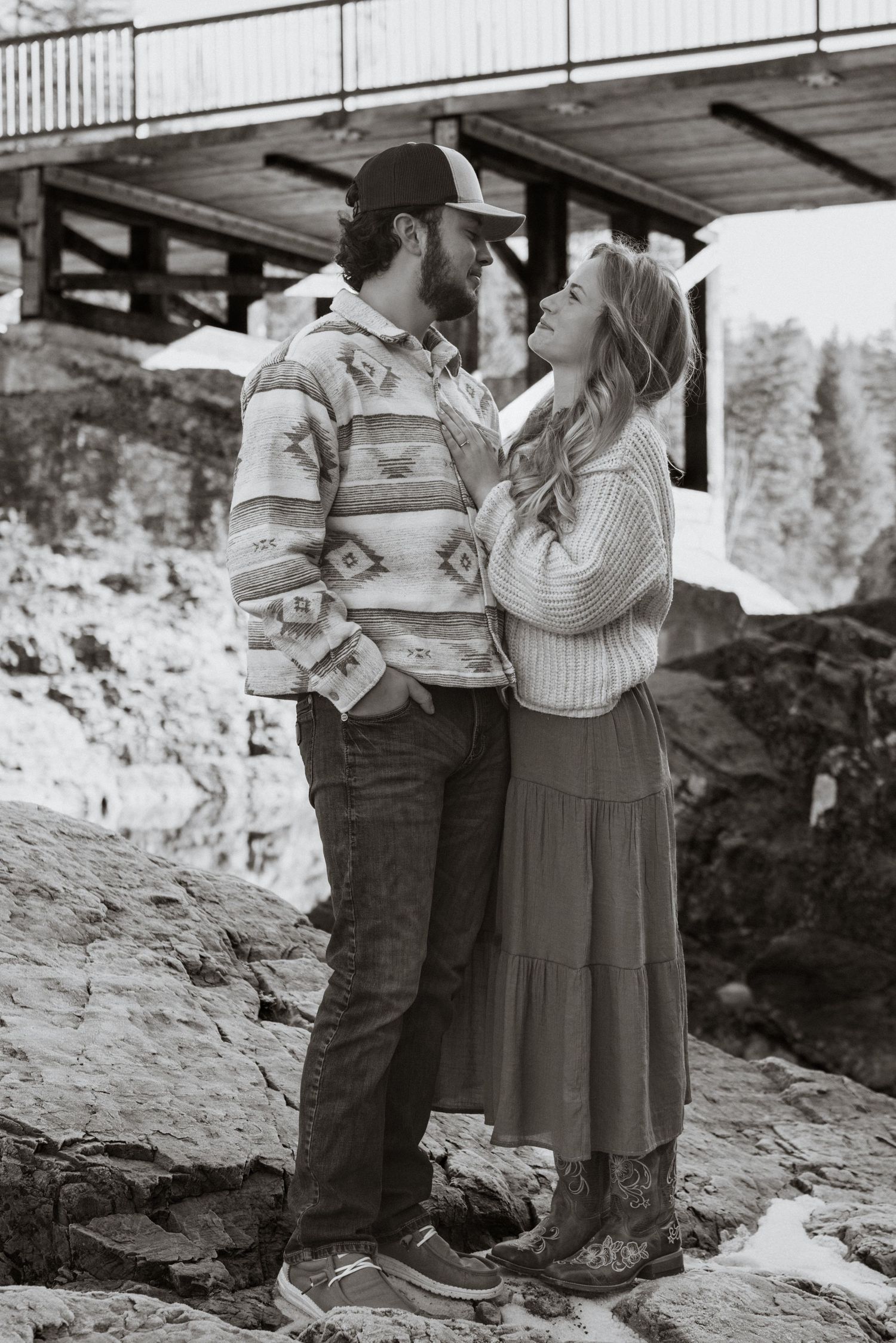 An engaged couple hugging and looking at each other with Belton bridge in the background in West Glacier Montana