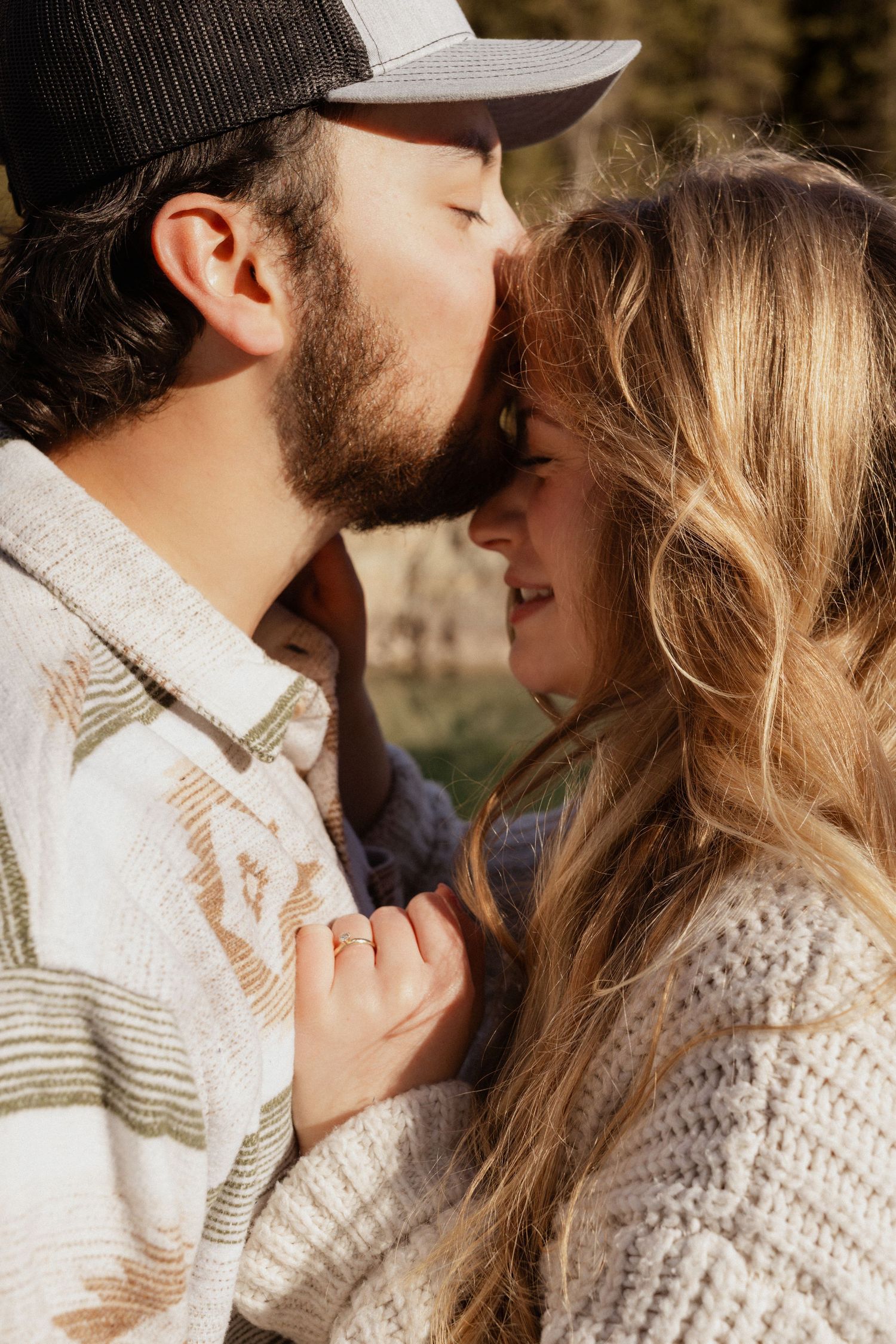 A man kissing a women's forehead during an engagement session in West Glacier Montana