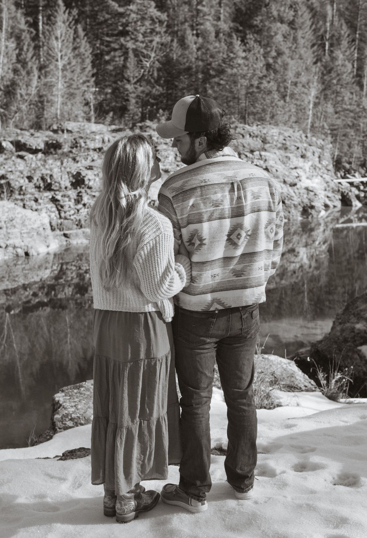 A couple standing close together looking at each other next to a river during a couples session in West Glacier Montana