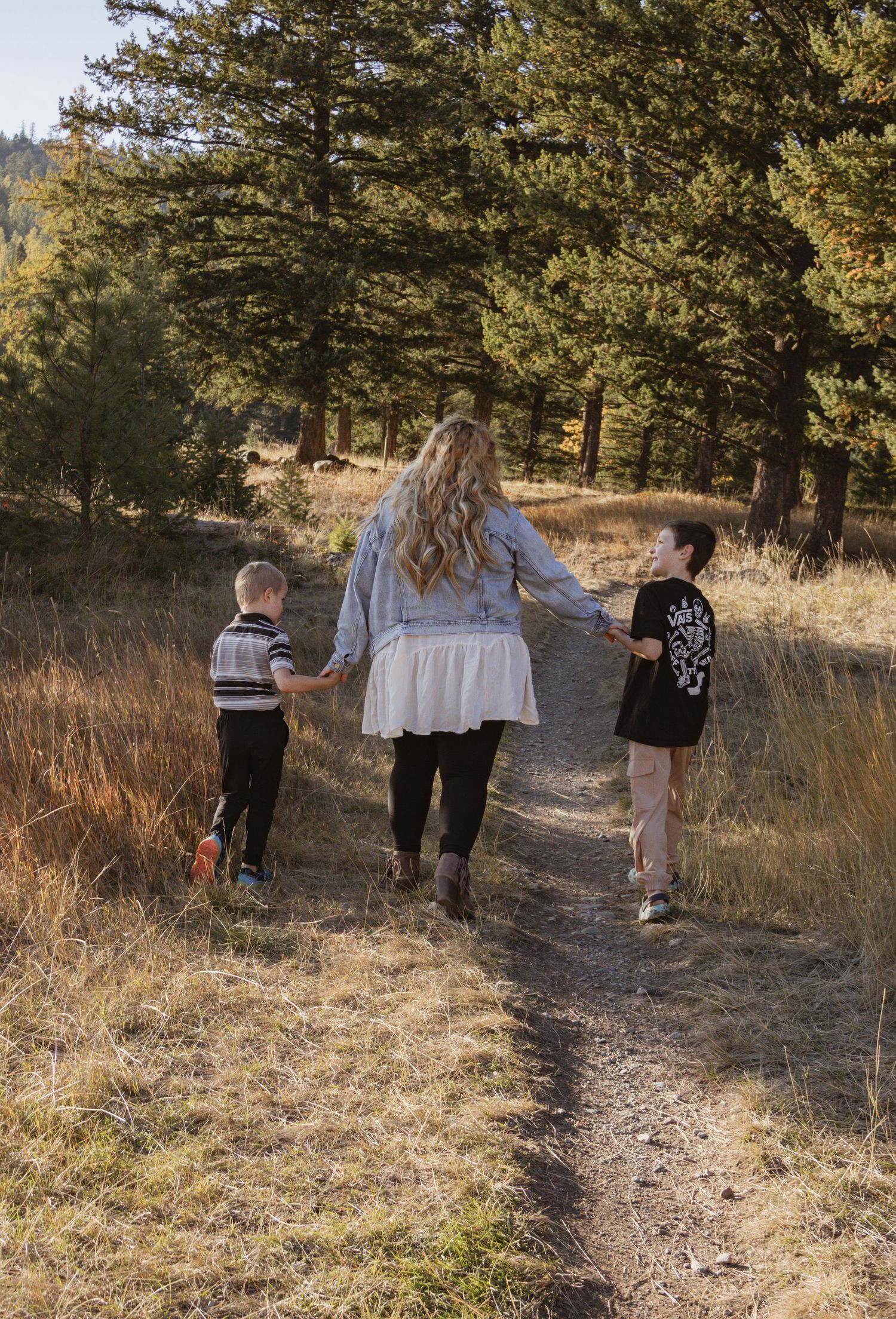 Mother and sons holding hands and walking together during a fall mommy and me session in Kalispell Montana