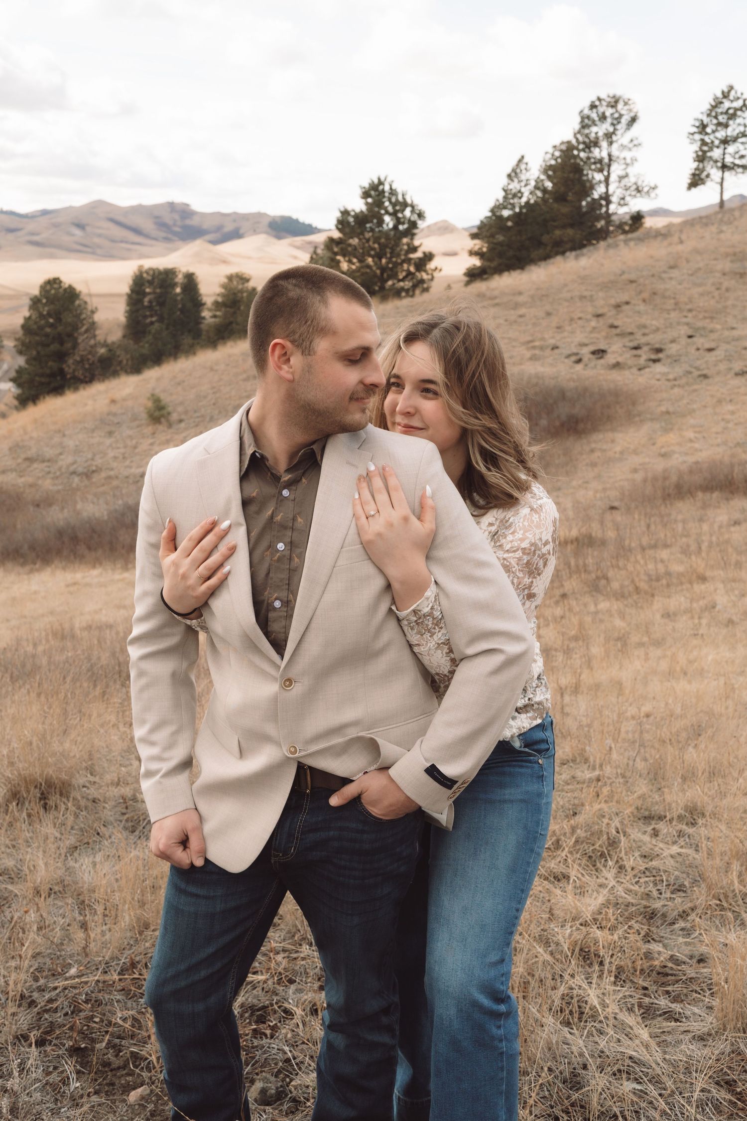 An engaged couple embracing on a hillside during an engagement session in Havre, Mt