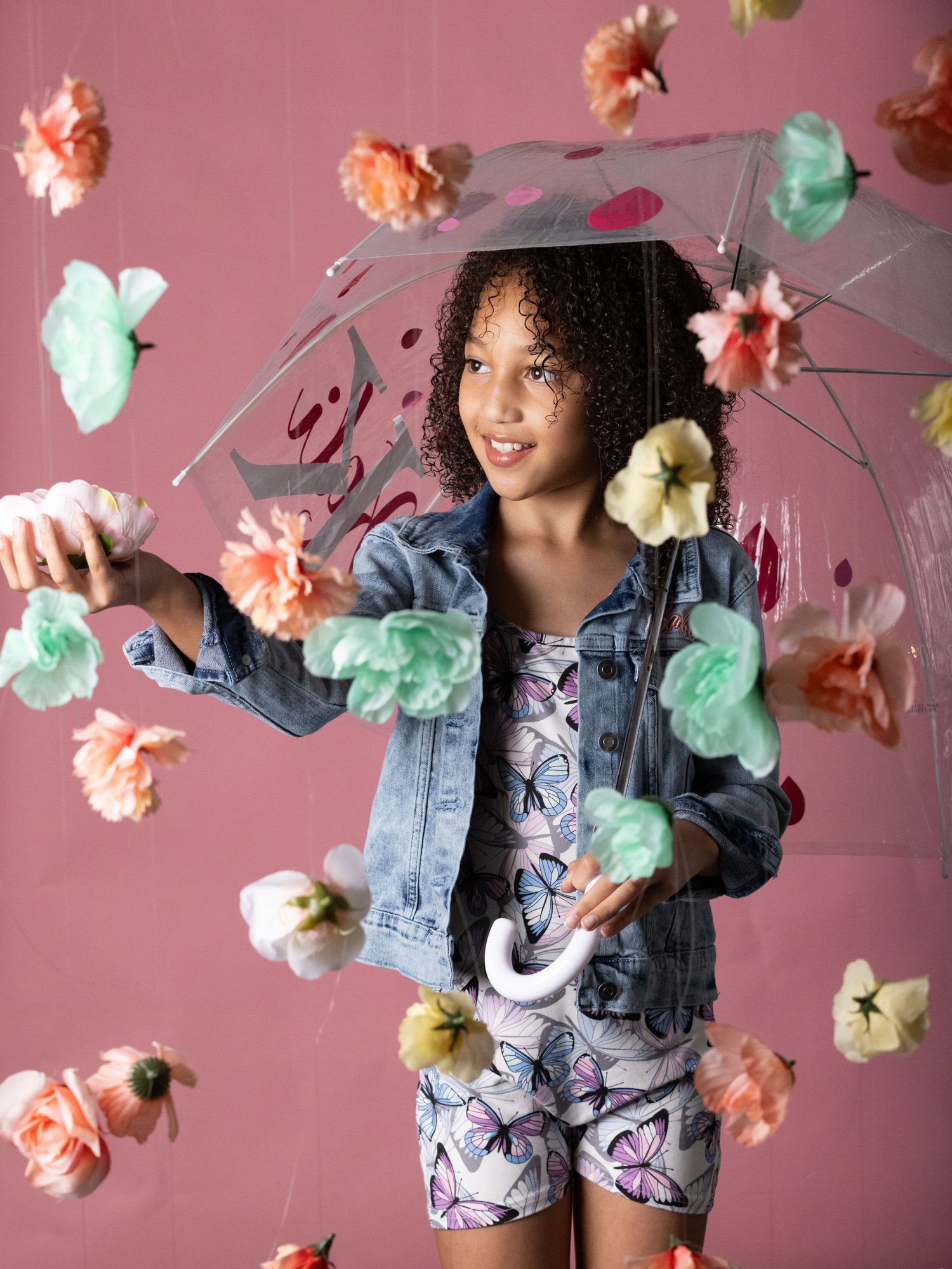 Cotton candy clouds in pink and mint float around a figure wearing denim against a dusty rose backdrop.