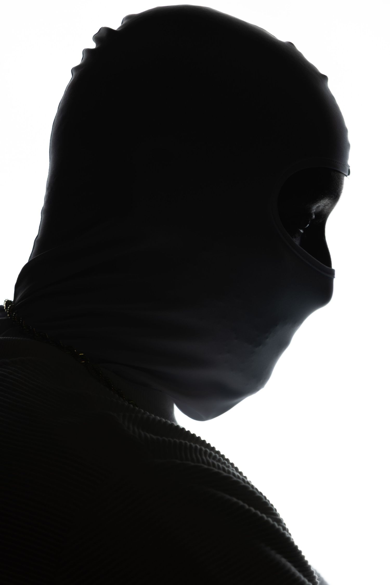 Dramatic silhouette profile of a person wearing a hooded garment against a white background.