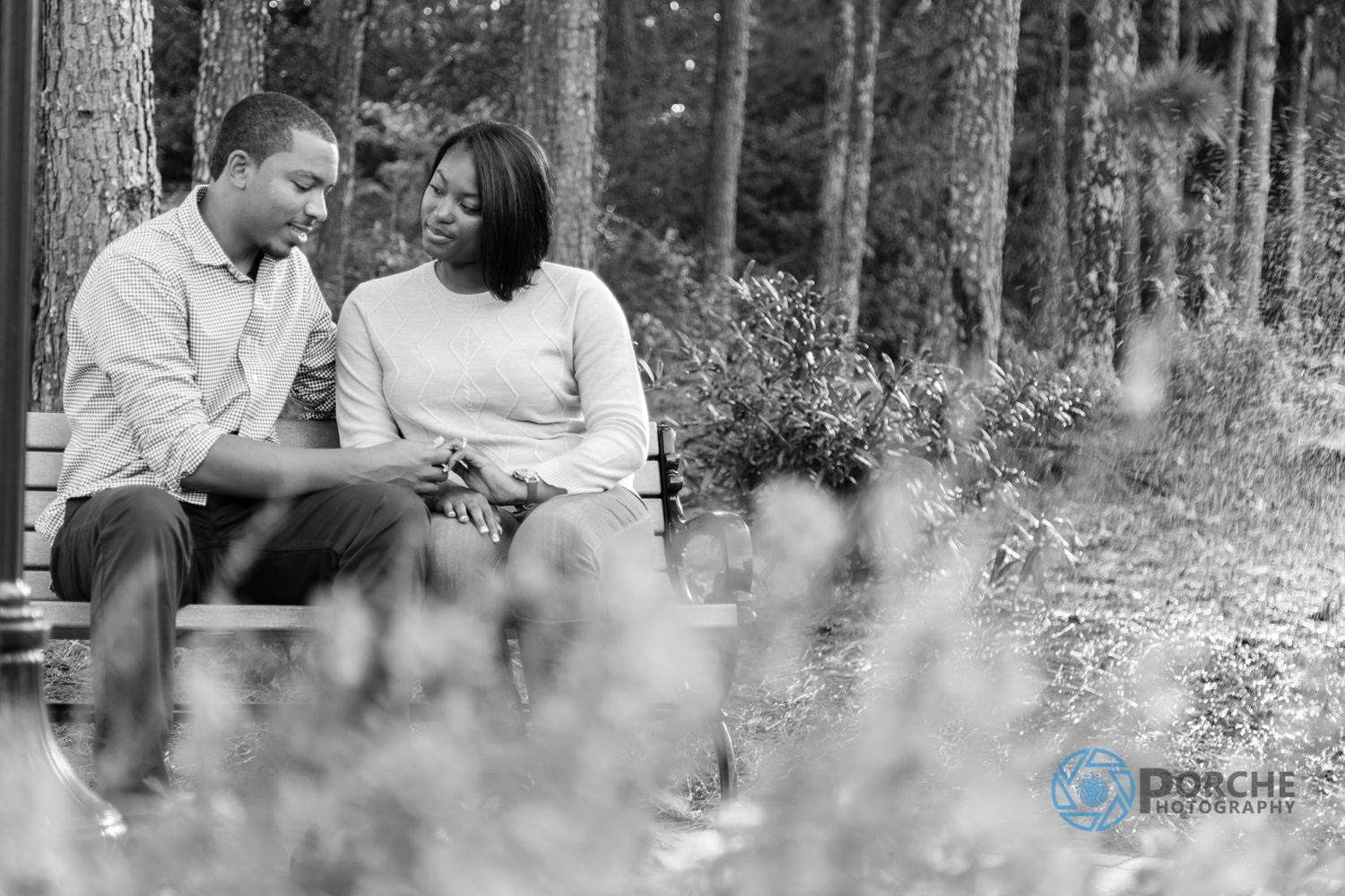 A couple shares intimate moments in black and white photos taken outdoors in a natural setting.