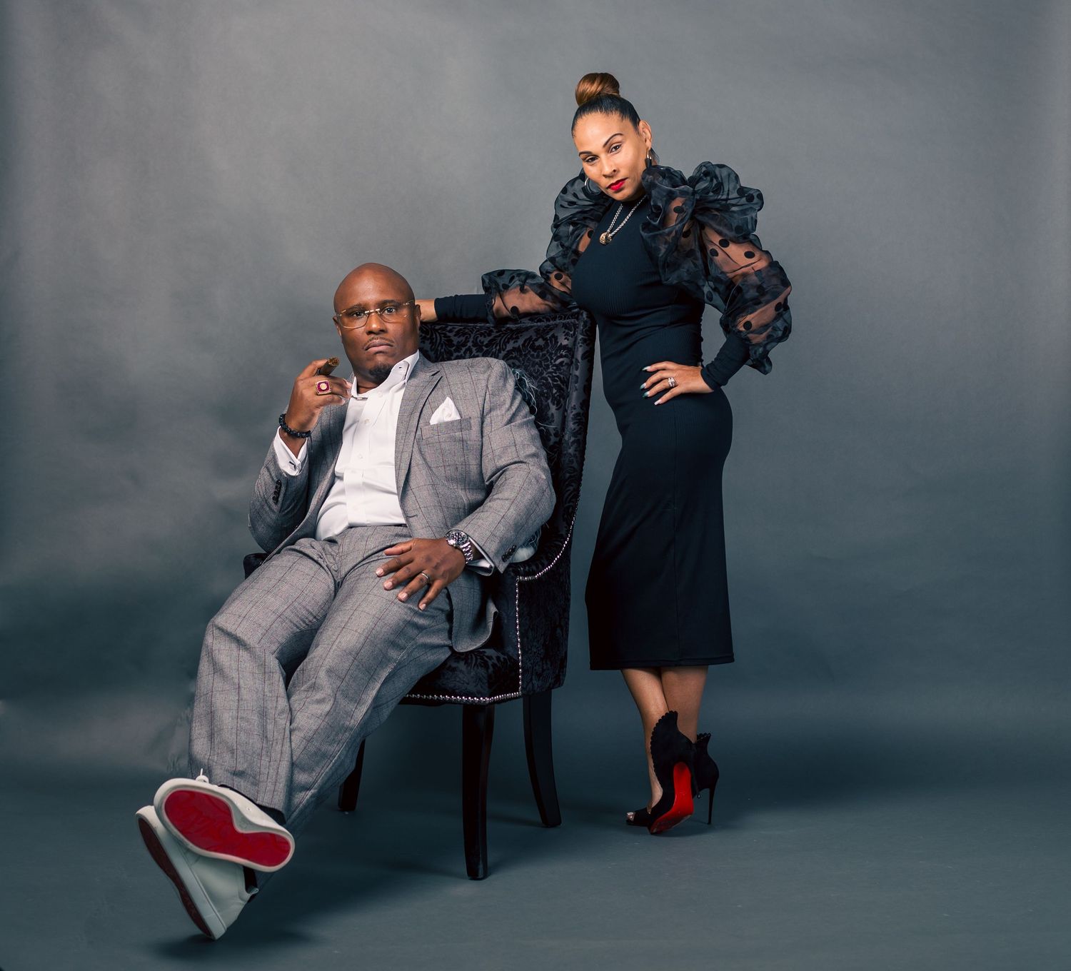 A creative photo series showing someone in a gray suit and red shoes posing with a chair against a dark backdrop.