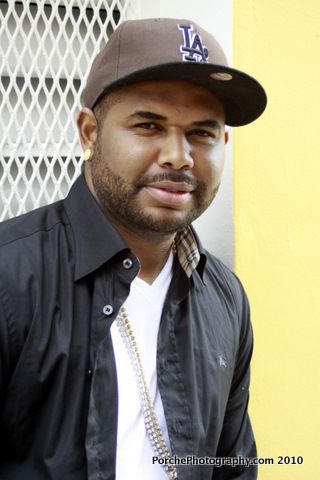 A person wearing a black jacket and LA baseball cap poses against a yellow wall in a series of headshots.