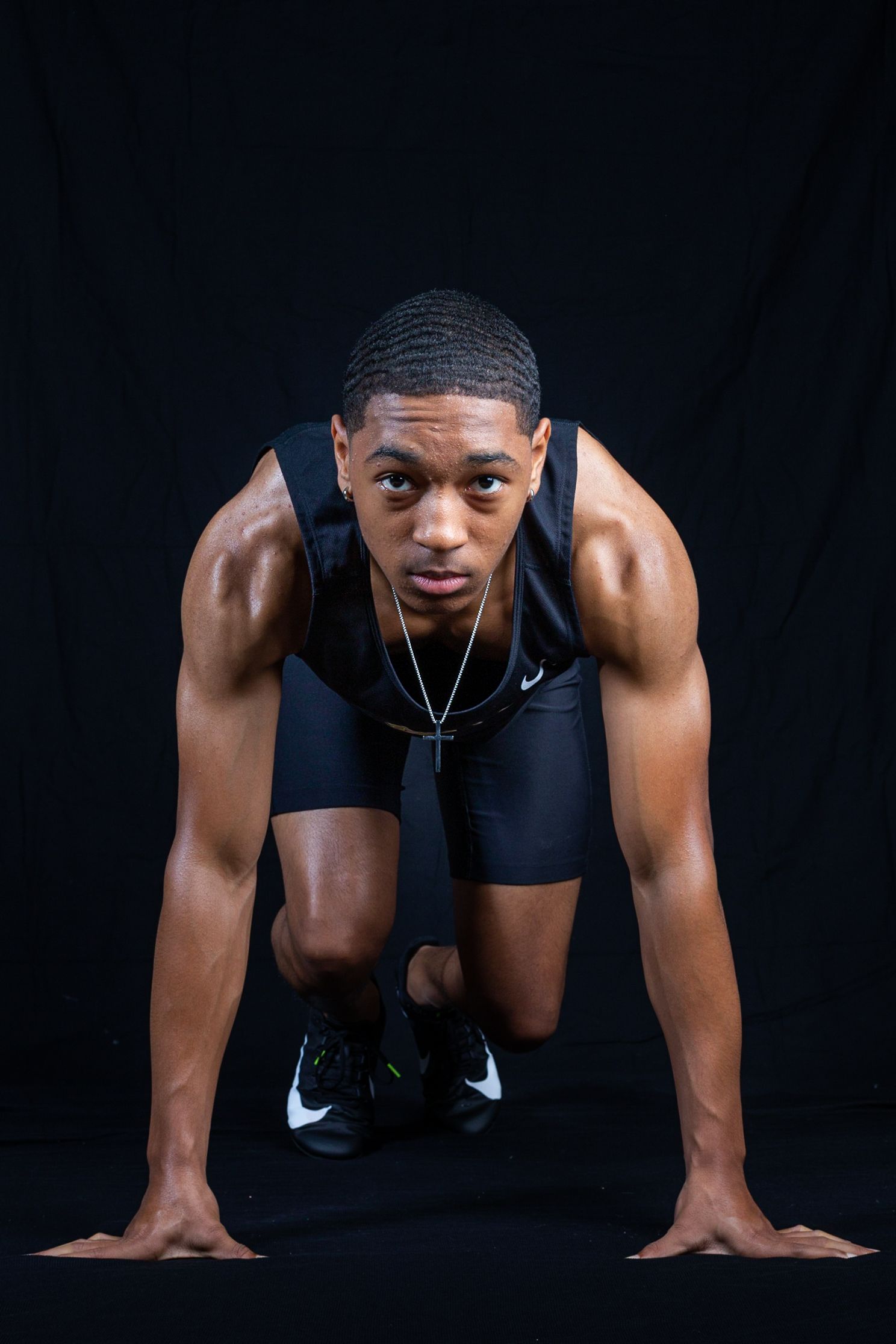 Athletic person in black Nike workout gear performs plank exercise poses on dark background.