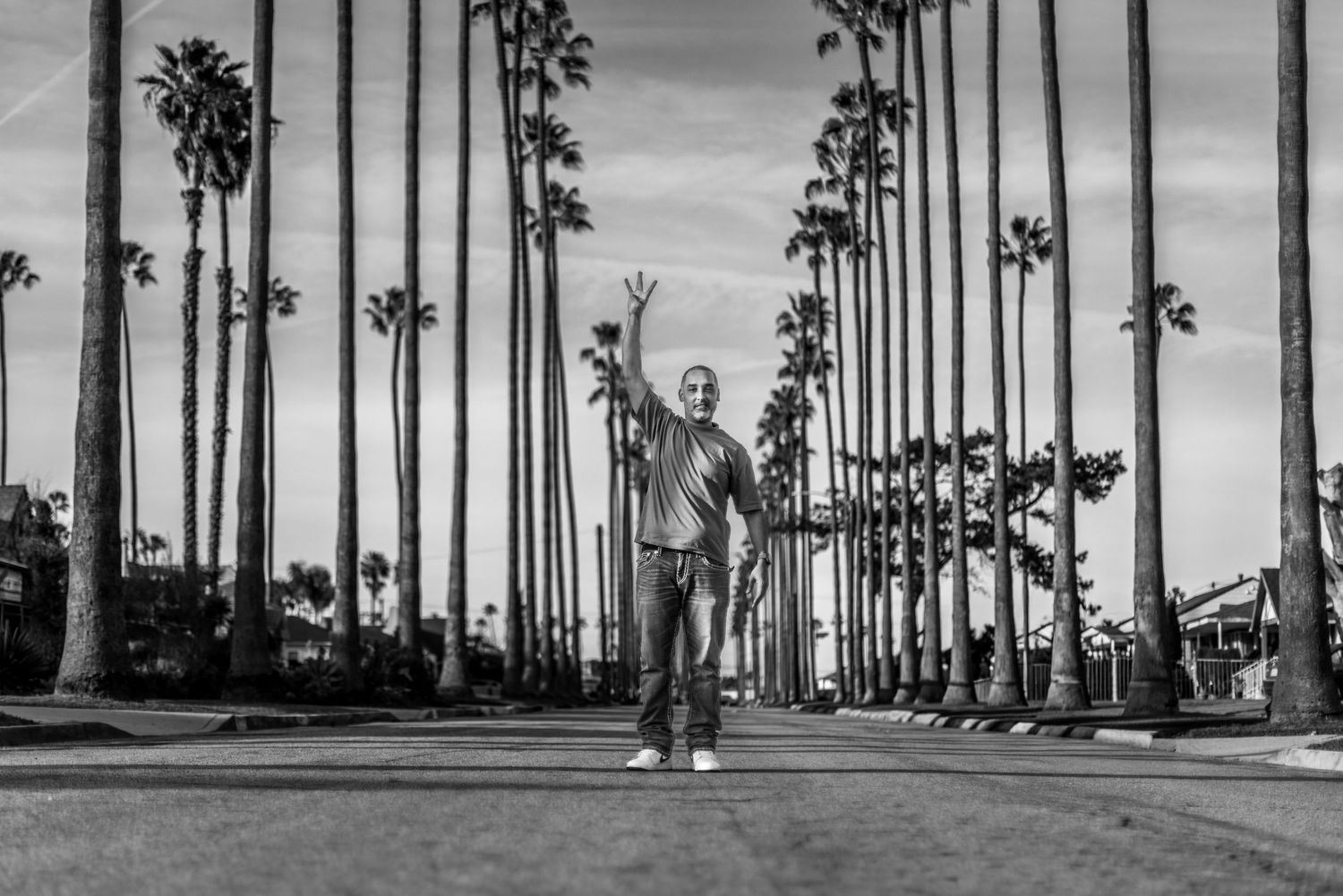 Black and white photo of someone standing on a palm tree-lined street in Los Angeles.