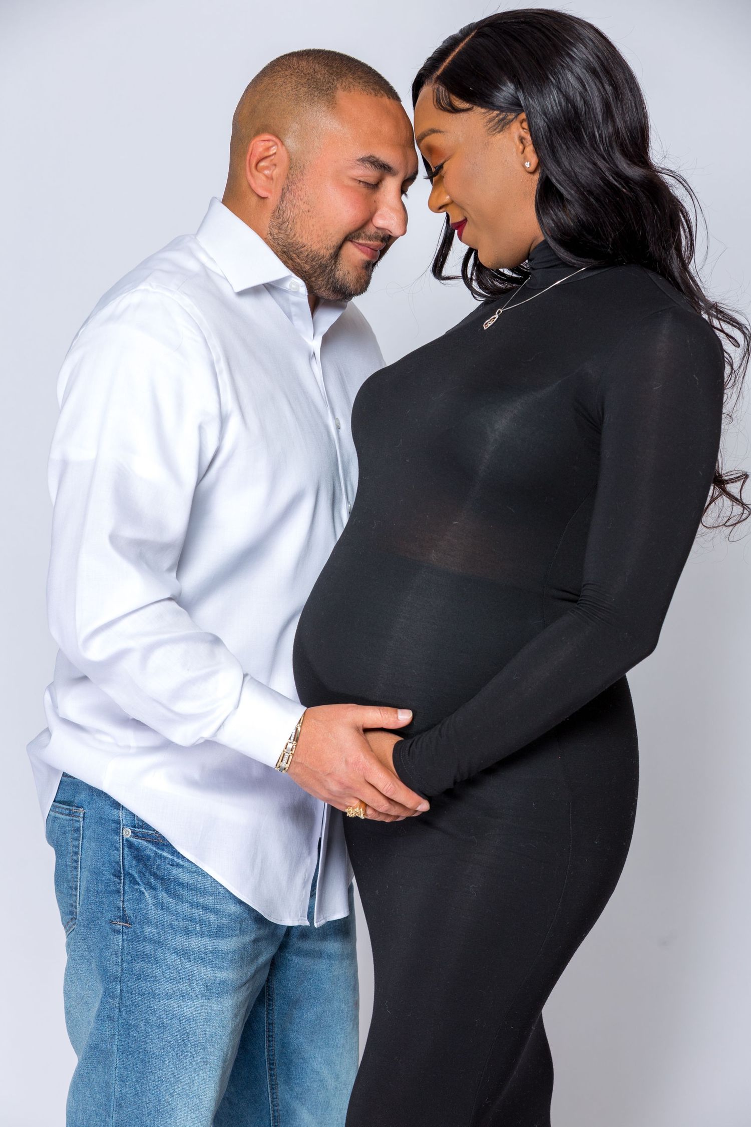 A couple shares an intimate moment in a studio setting wearing contrasting black and white outfits.
