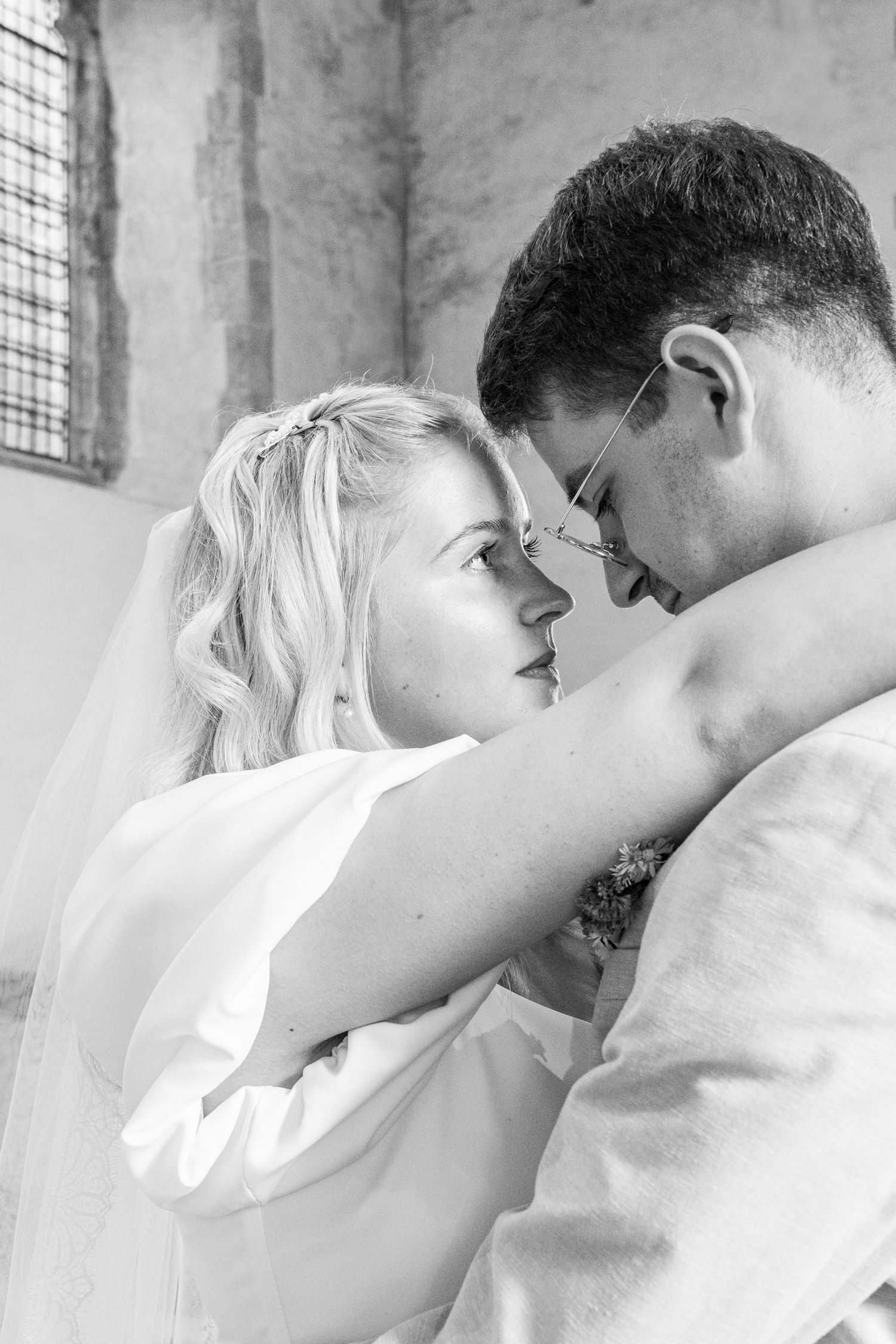 Black and white romantic portrait of bride and groom touching foreheads in intimate moment.