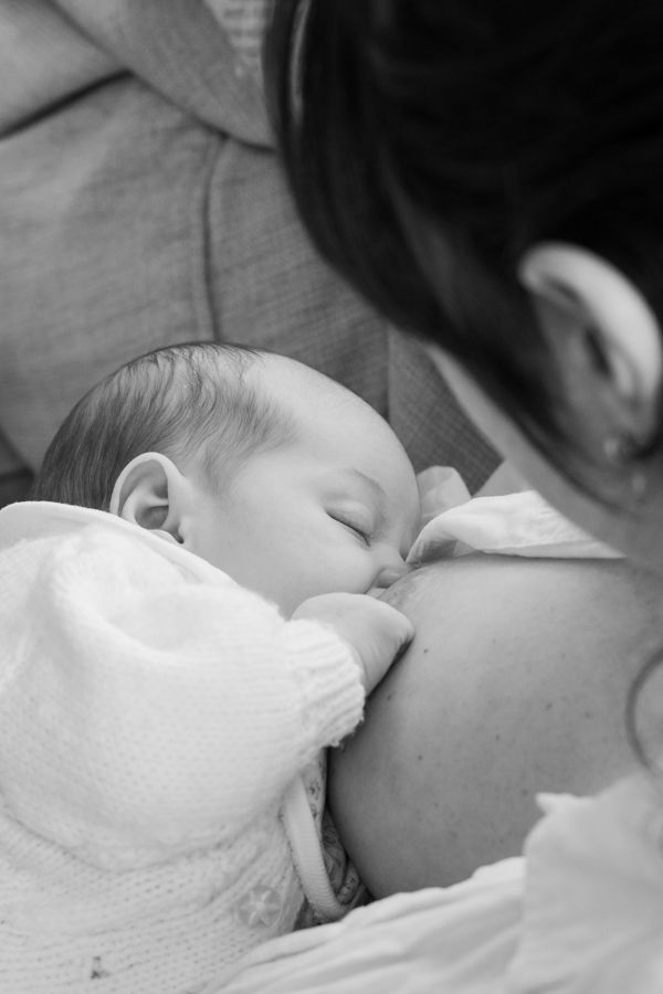 Black and white image of a mother breastfeeding her sleeping newborn baby.