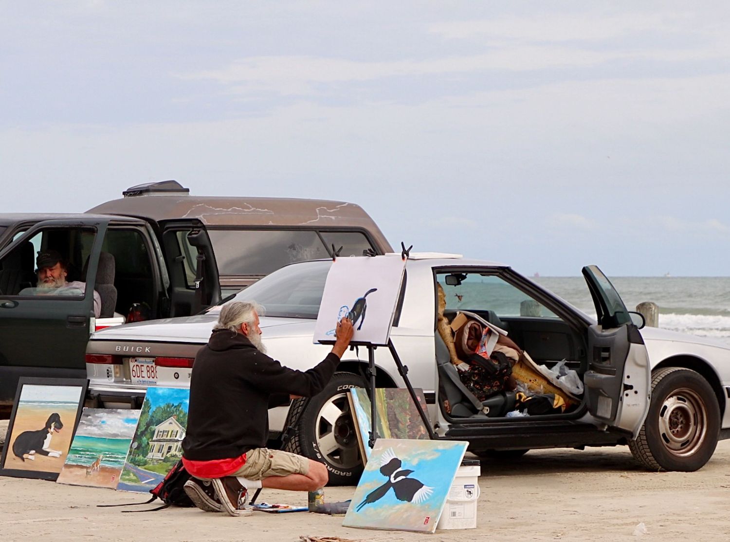 Artist living out of a car painting on canvas along the Texas coast near the beach.