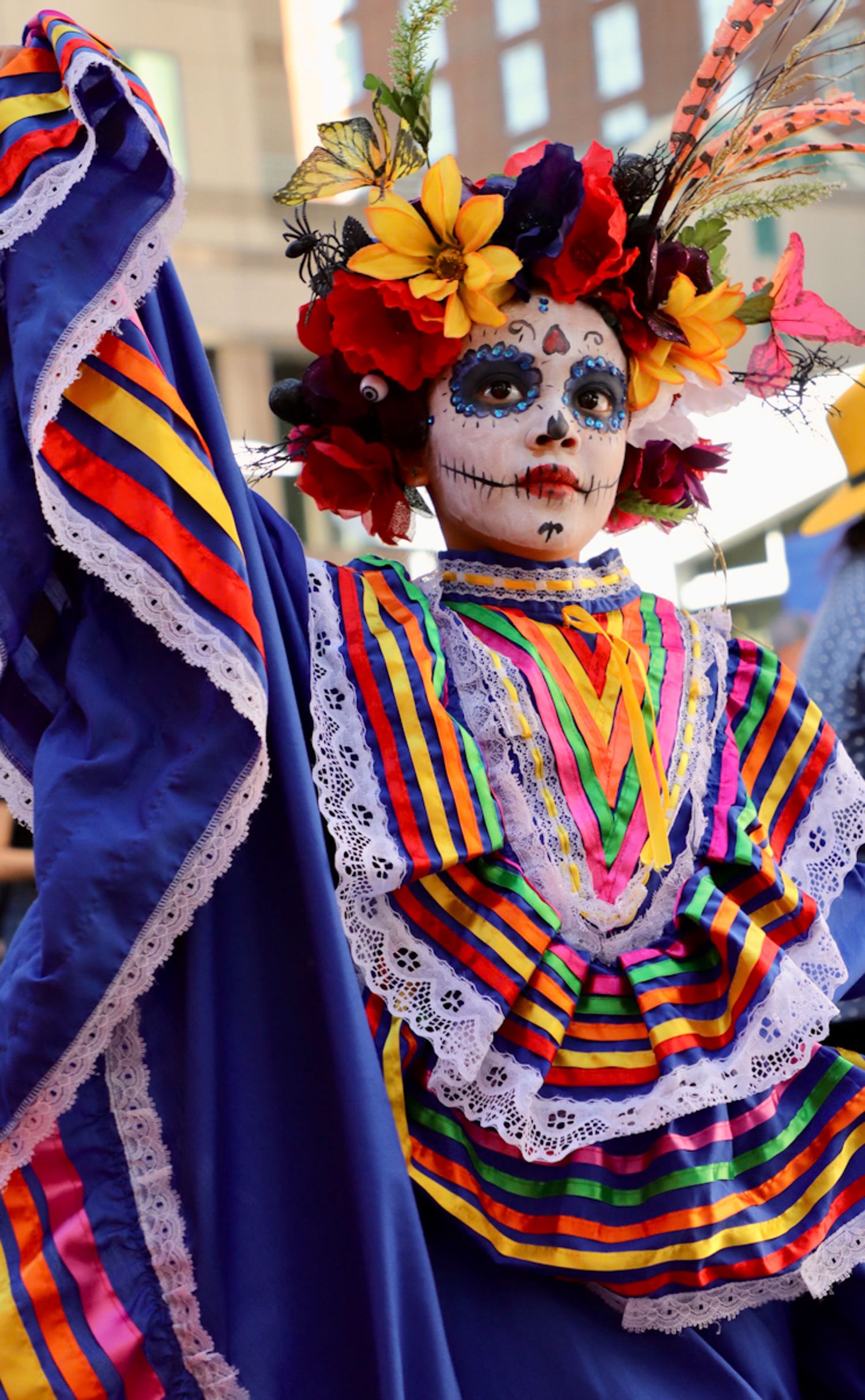 Child dressed in colorful traditional attire with Día de los Muertos face paint, capturing cultural celebration and heritage.