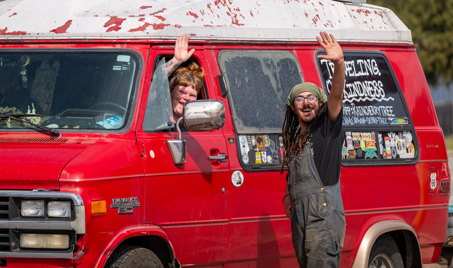 People waving from a red van in rural Texas, capturing a candid moment of community and everyday life.