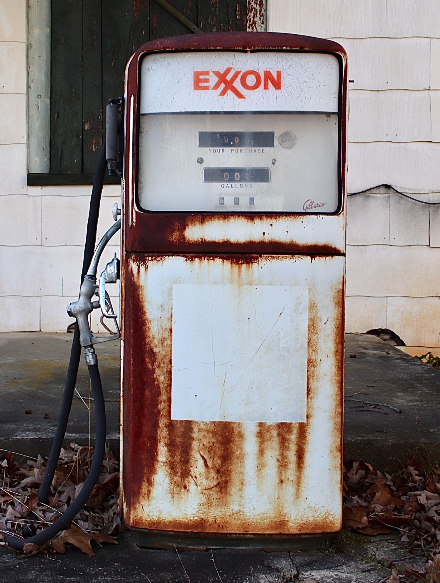 Vintage Exxon gas -covered vintage gas pump standing outside a weathered rural building, reflecting the passage of time in small-town..