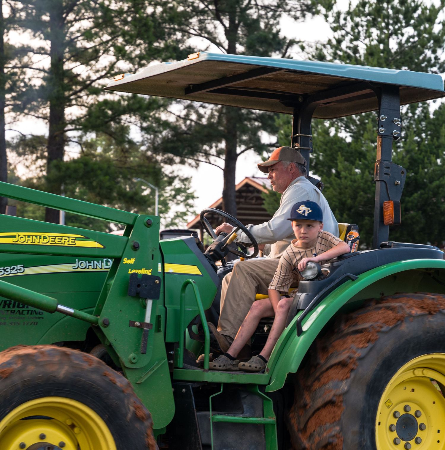 Farmer and child riding together on a tractor, capturing generational life and tradition in farming community.