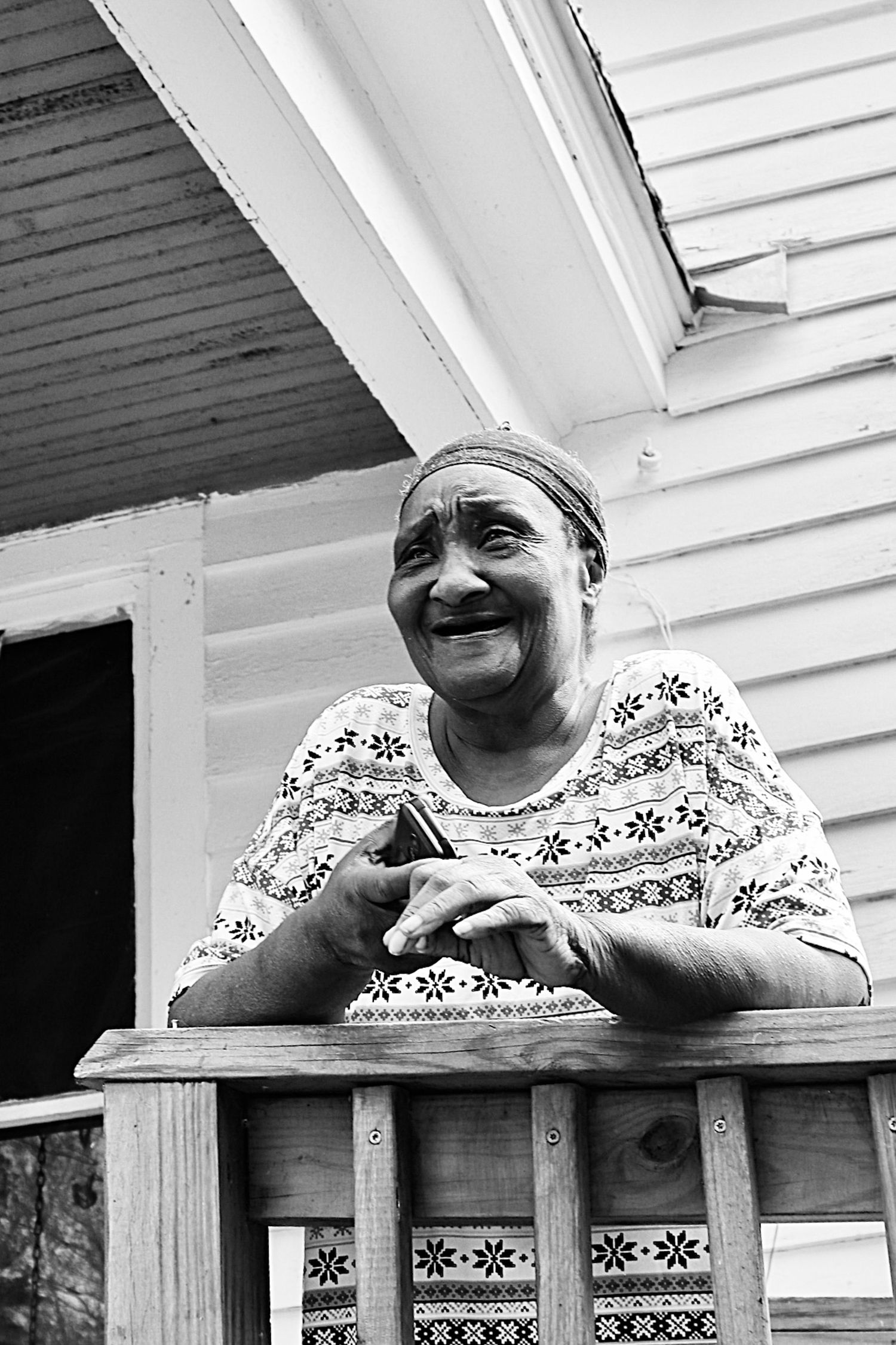 Woman standing on a porch in a rural community, captured in a candid moment reflecting everyday life and personal connection.