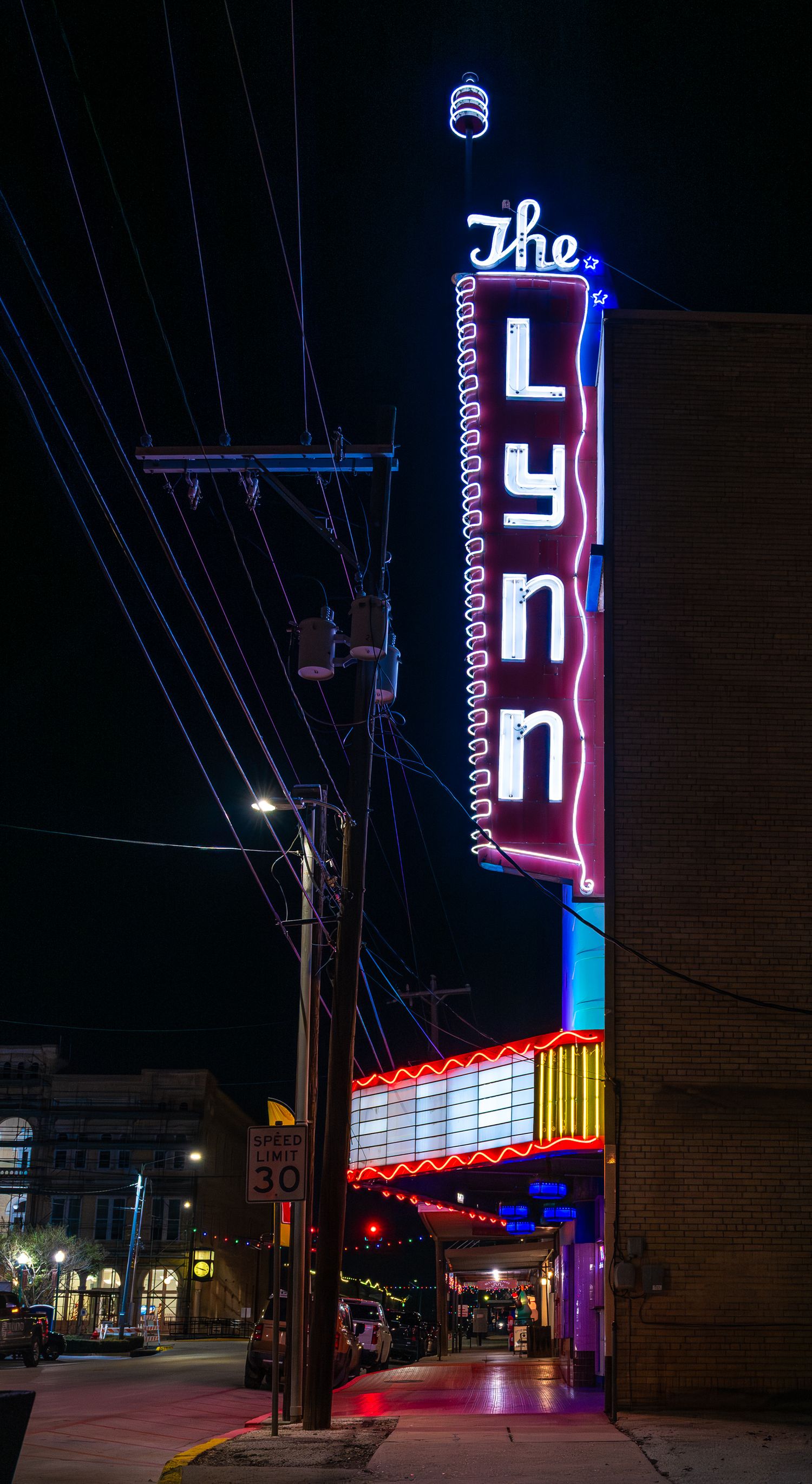 The Lynn Theater  neon sign illuminates a quiet downtown street in Gonzales Texas at night, capturing small-town atmosphere and nostalgia.